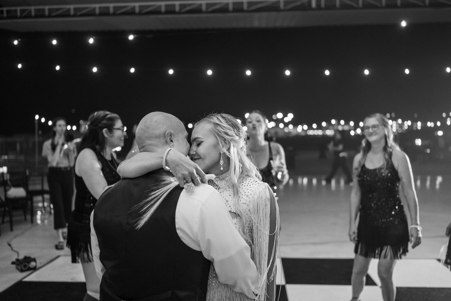 Black and white photo of bride and groom sharing intimate dance embrace at outdoor evening wedding reception.