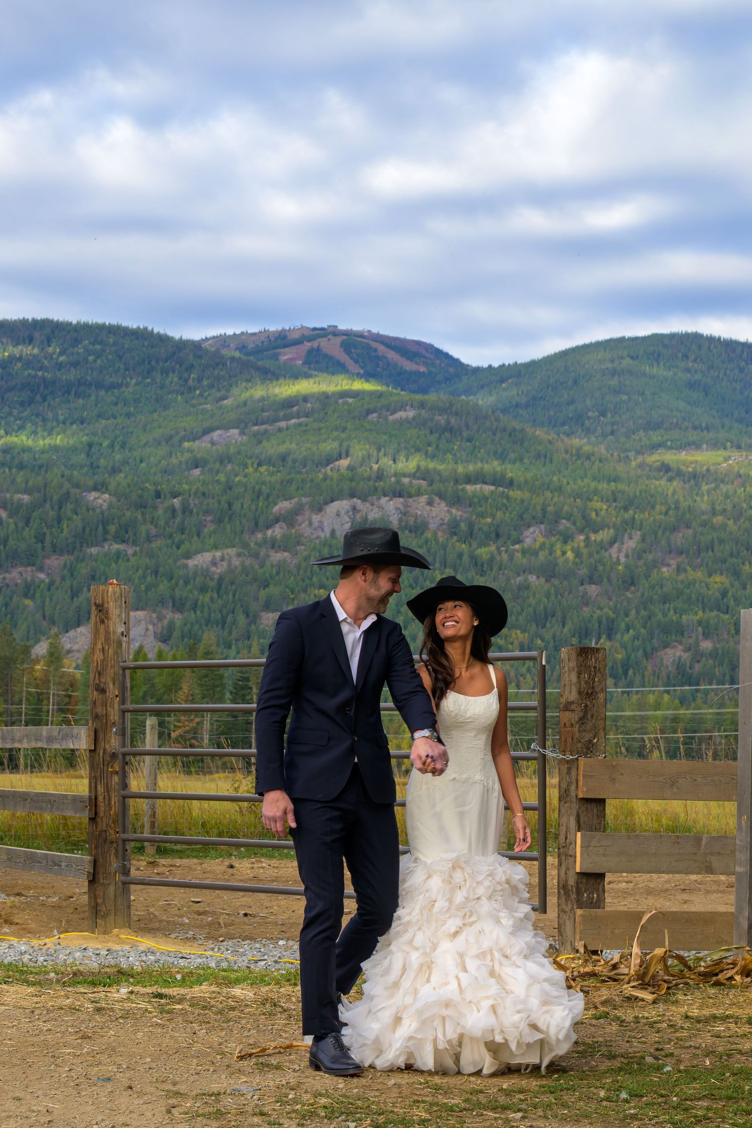Couple sitting on rustic fence with mountain landscape in autumn.
