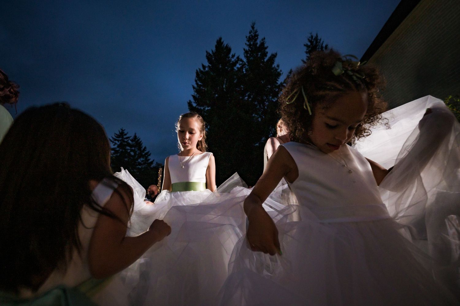 Silhouetted figures dance and celebrate at a lively outdoor wedding reception at dusk.