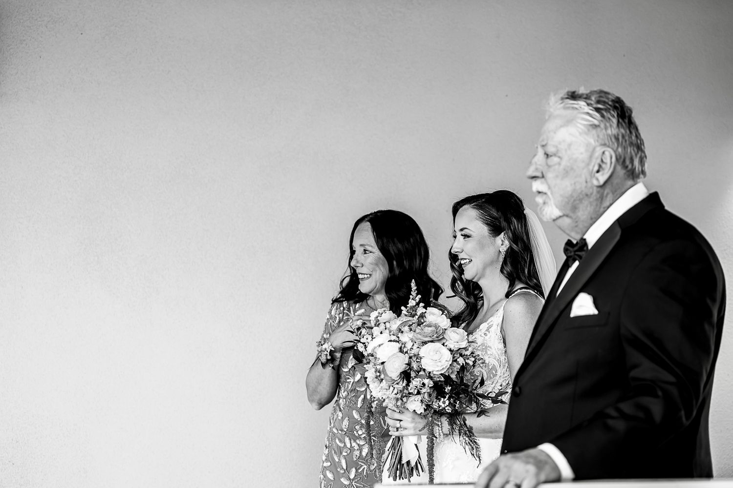 Black and white candid moment showing wedding party members with bouquets.