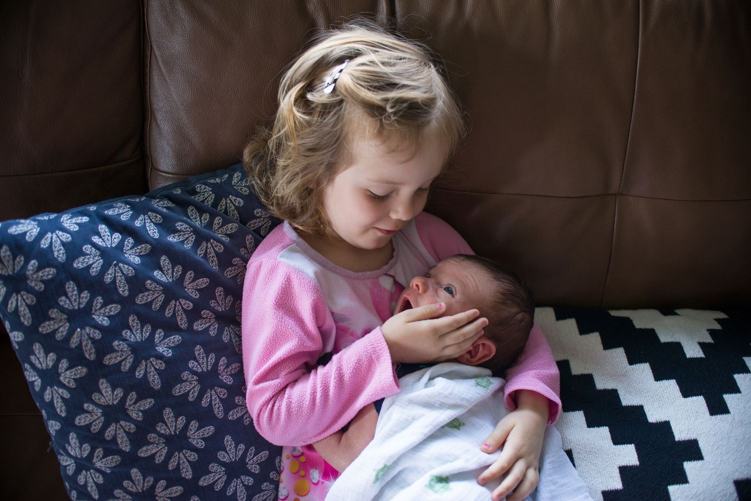 Young child in pink clothing relaxing on a black and white patterned blanket.