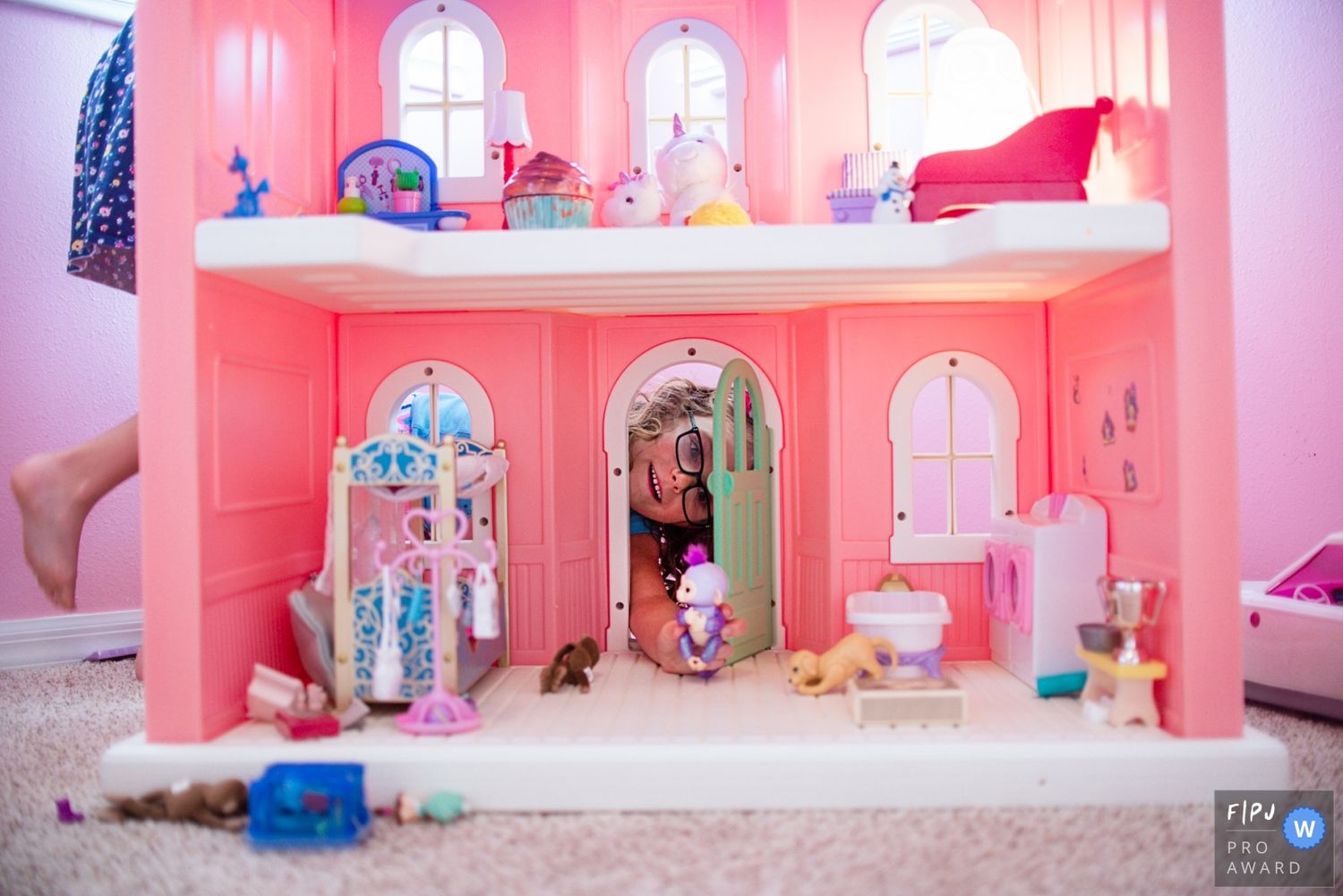 Pink dollhouse interior with miniature furniture and decorative elements arranged in multiple rooms.