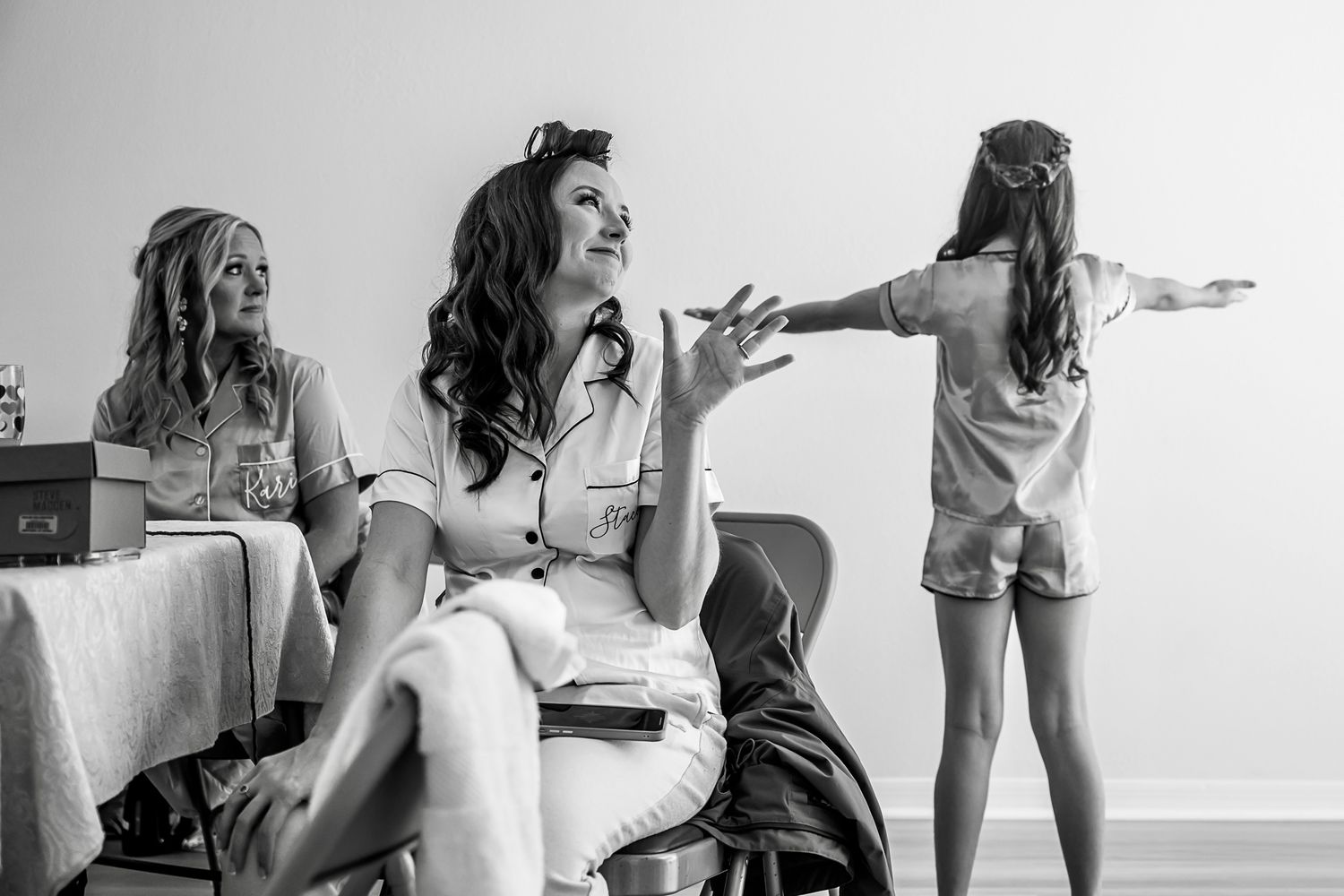 Black and white candid moment showing animated conversation and gestures between three women.