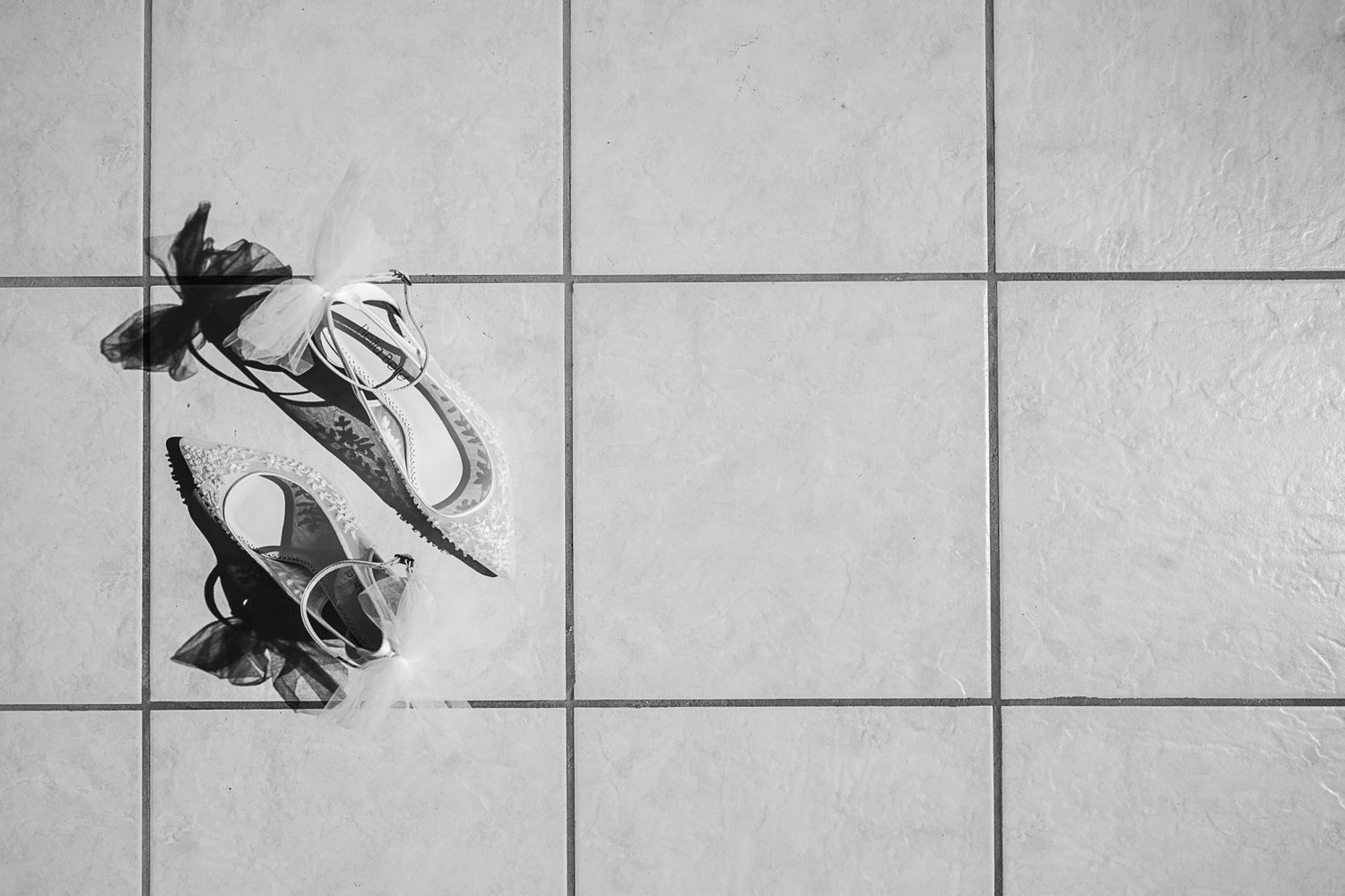 A pair of black and white sneakers resting on a tiled floor viewed from above.