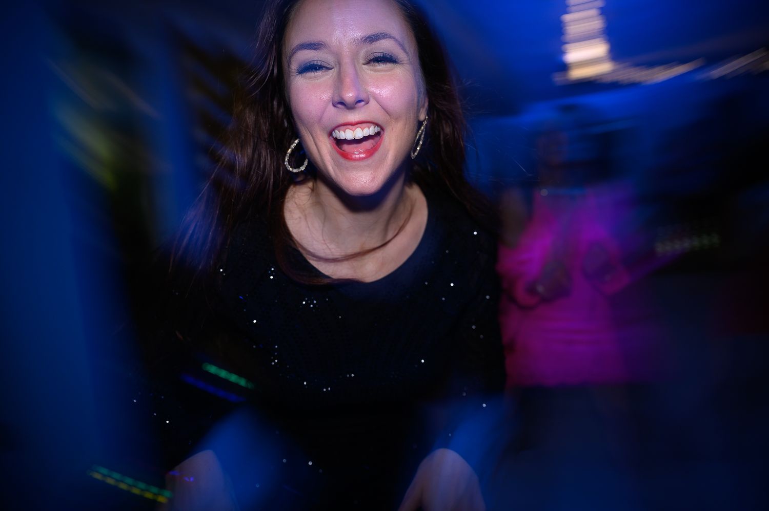 Dancing in a nightclub with blue lighting and motion blur creates an energetic party atmosphere.