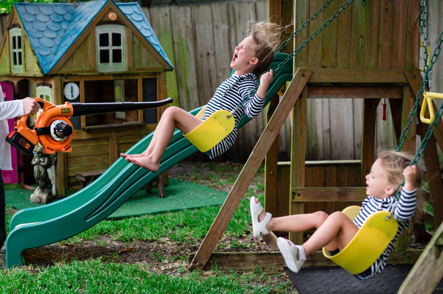 Children enjoying outdoor playtime on a backyard swing set with multiple swings and a slide.