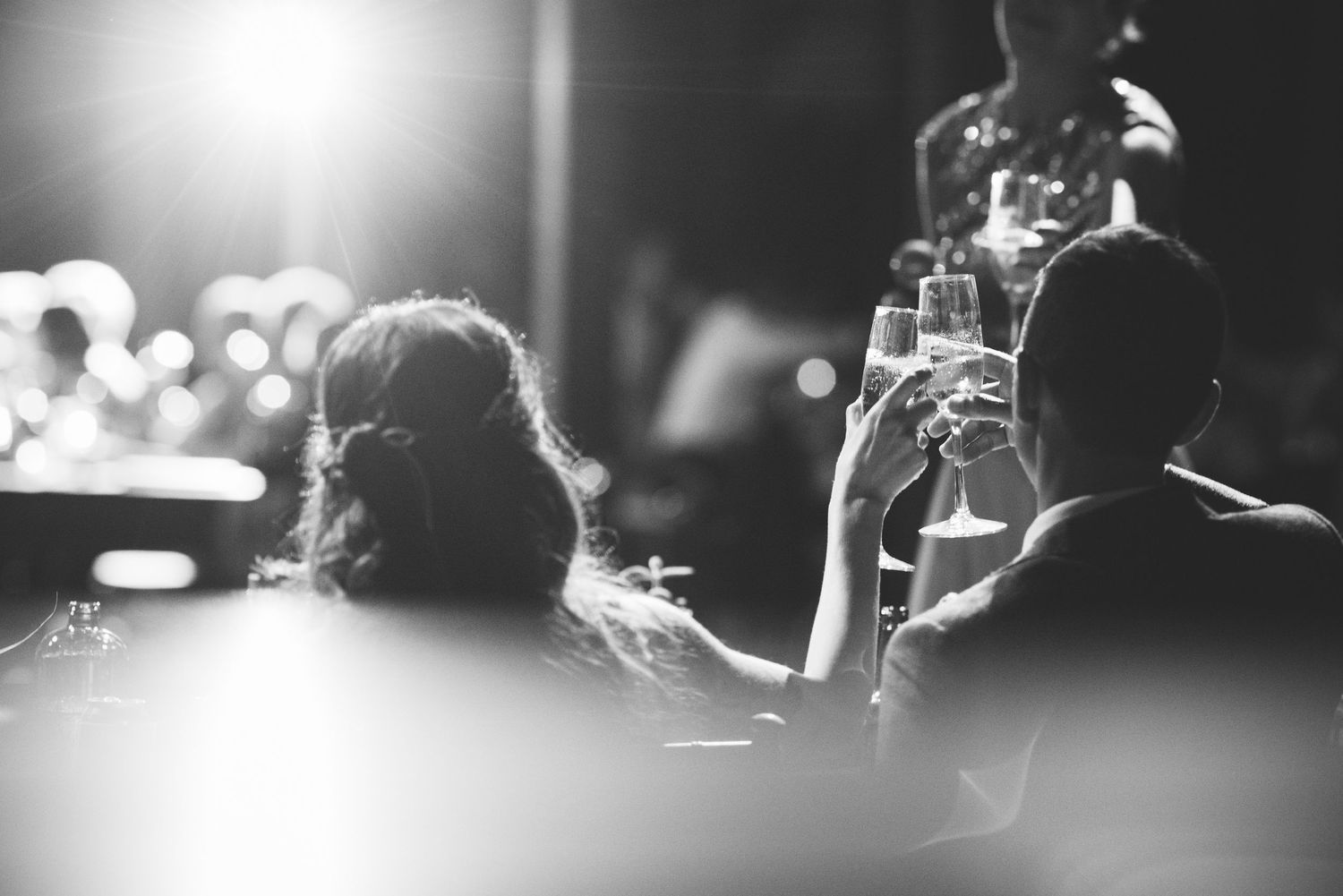 Wedding reception guests enjoying drinks and conversation at a dimly lit bar.