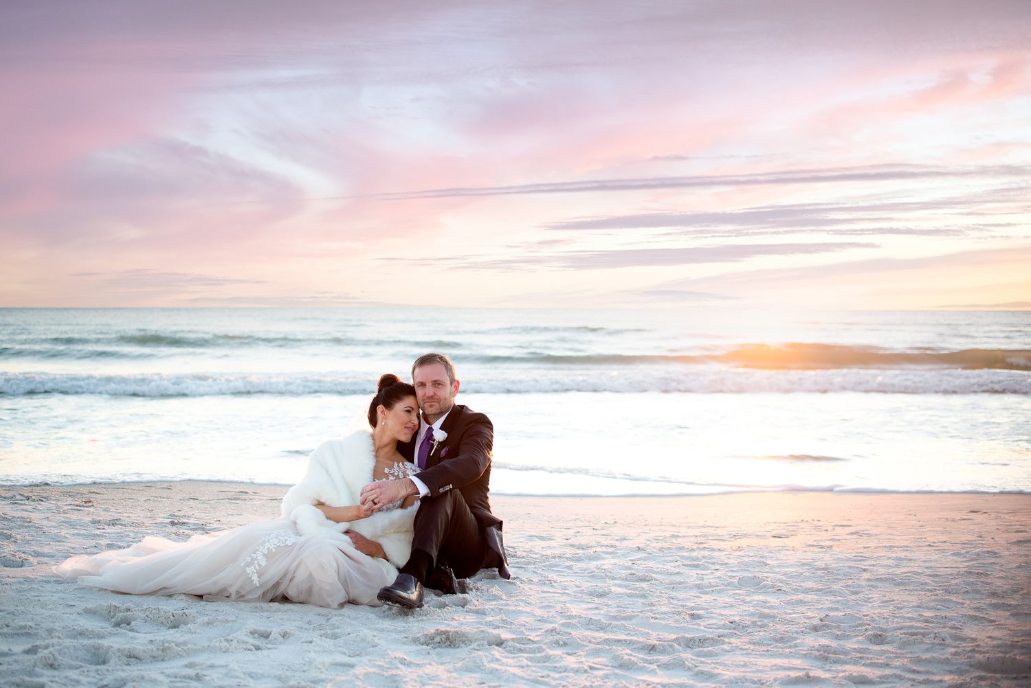 Dramatic sunset beach photos with waves splashing around wedding couple.