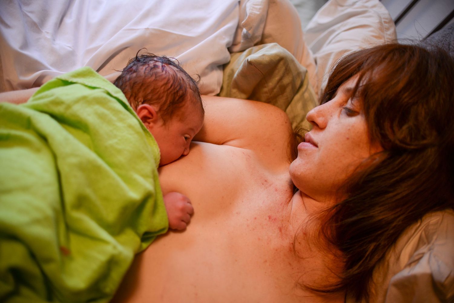 Newborn baby sleeping peacefully on soft bedding in natural light.