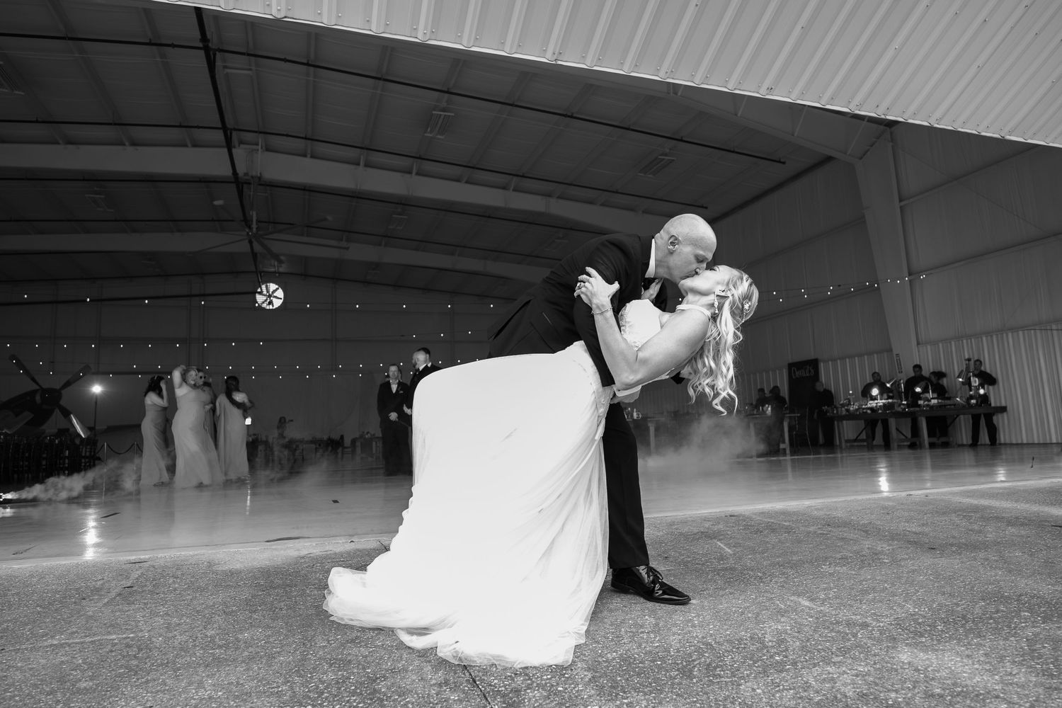 Bride and groom share a romantic dip kiss during their first dance at an elegant wedding reception.