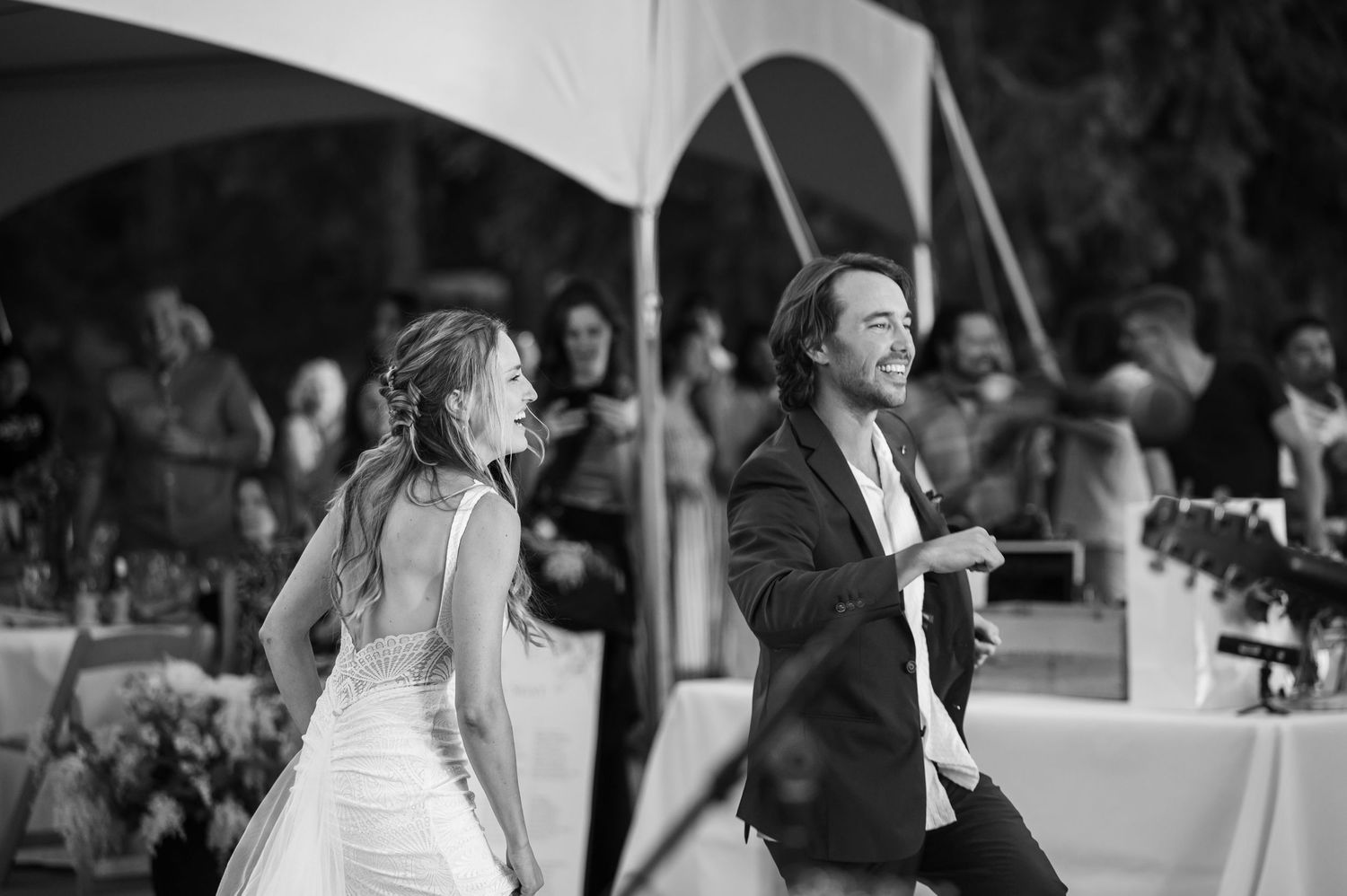 A couple sharing their first dance at a wedding reception, captured in elegant black and white photography.