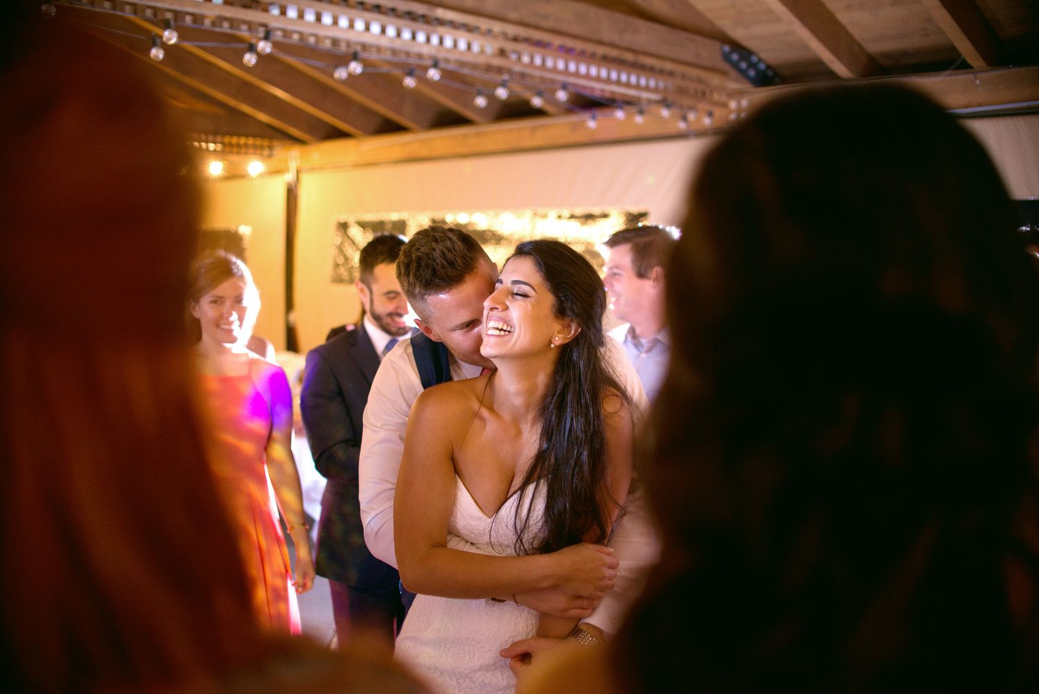 Indoor wedding celebration with string lights illuminating dance floor festivities.