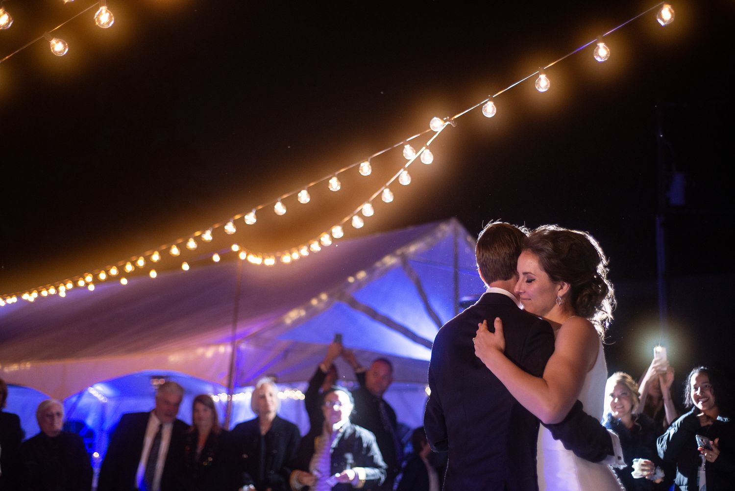 Wedding reception dance floor under glowing string lights creating magical atmosphere.