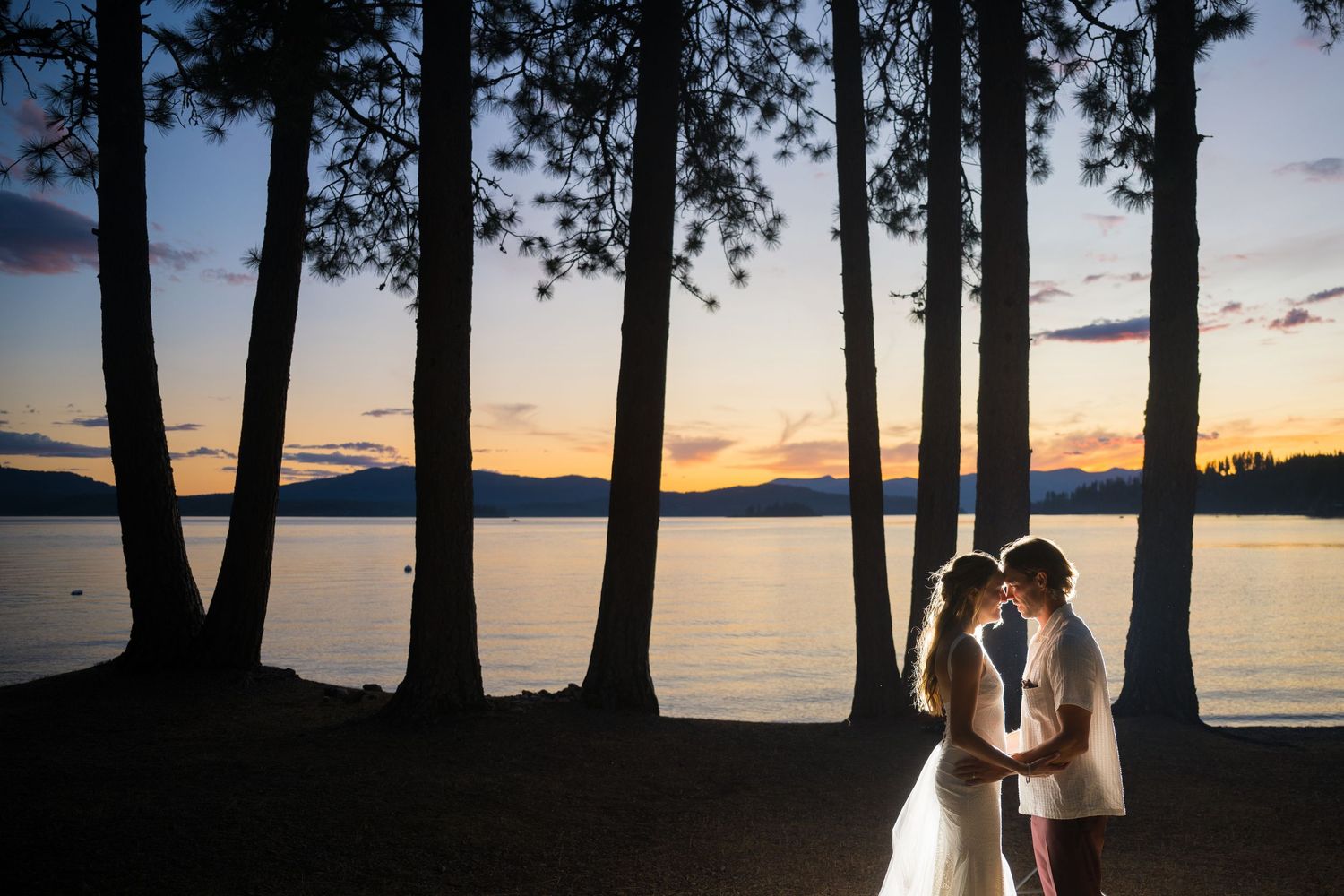 Silhouetted trees against a sunset lake backdrop creating a romantic atmosphere.