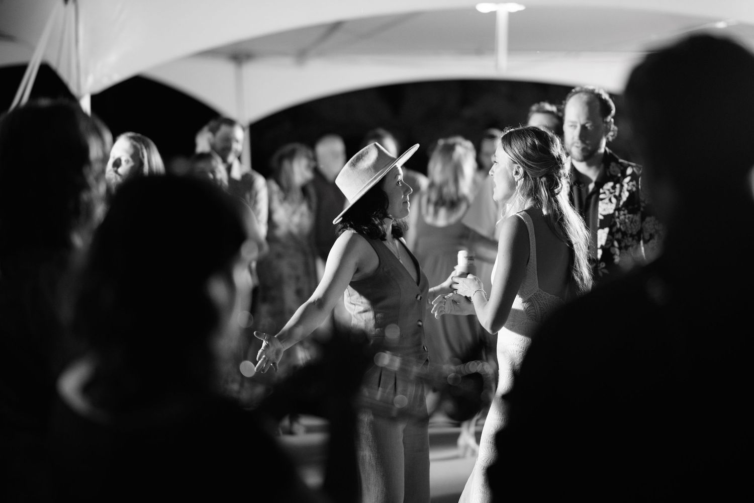 Black and white photo of a crowded dance floor under tent at a wedding reception.