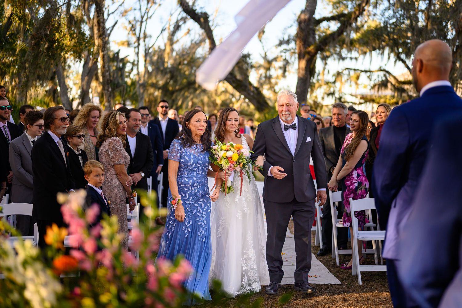 Wedding guests gather outdoors at sunset during a garden ceremony celebration.