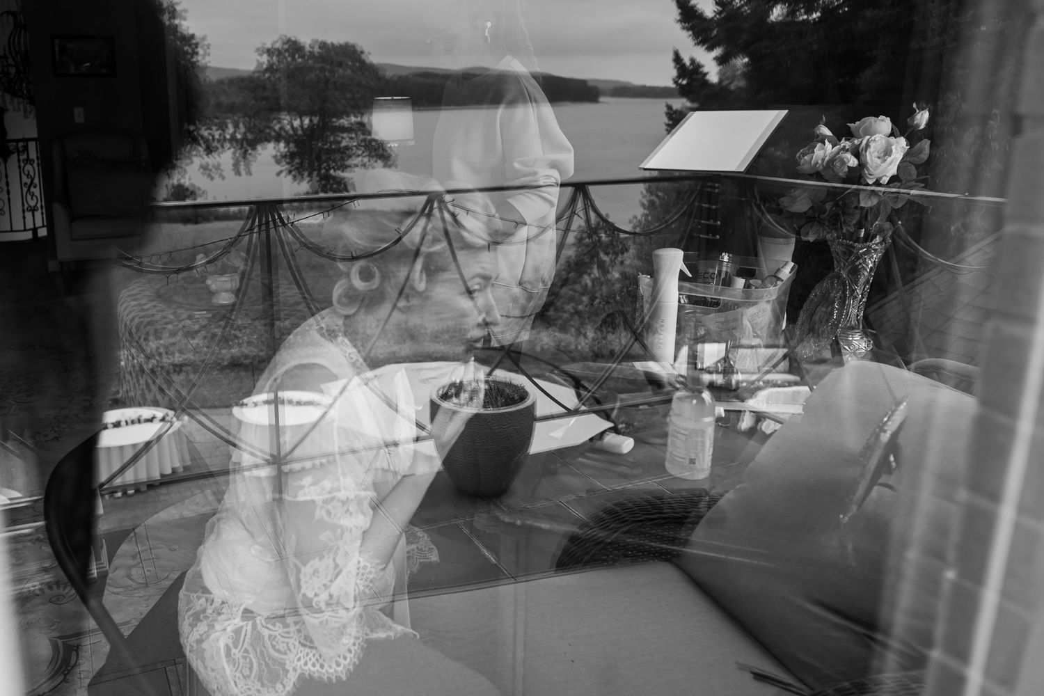 Double exposure black and white photograph showing a reflection of boats on a lake through a window.