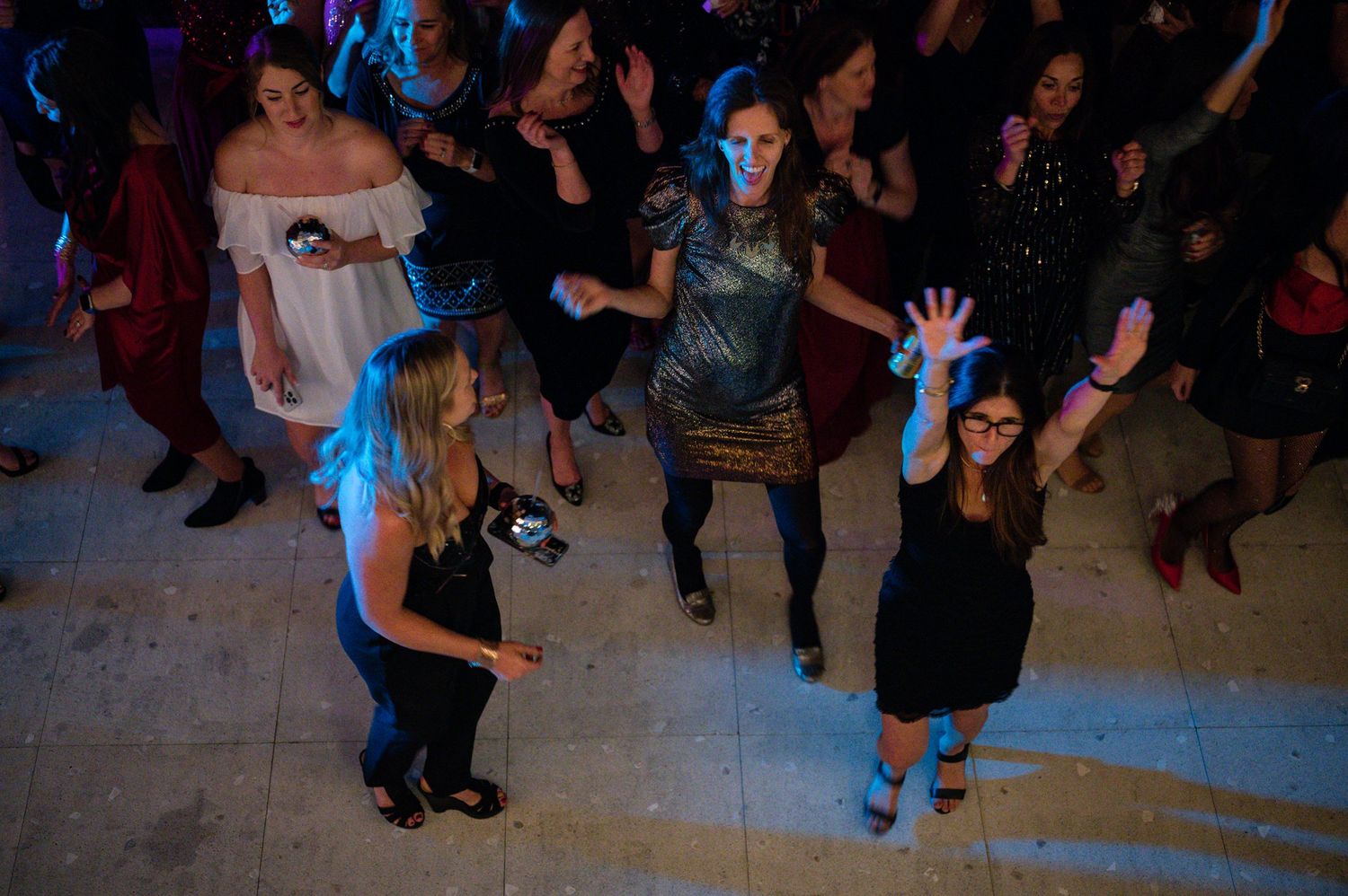 Party guests dancing on a blue-lit dance floor during a nighttime celebration.