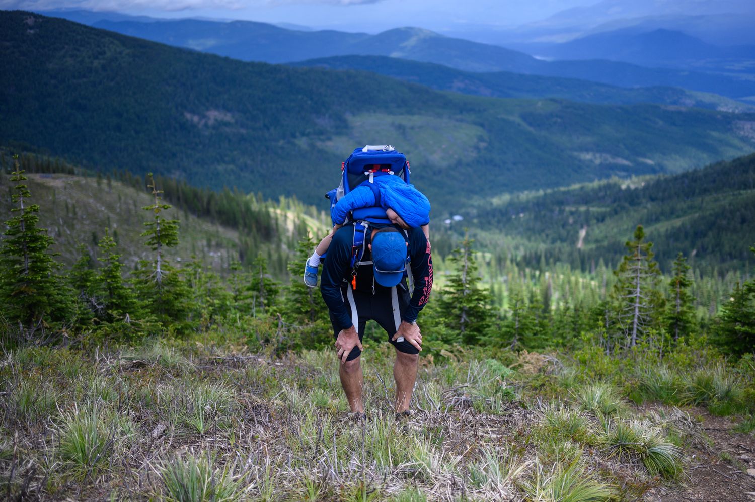 Scenic mountain landscape views with hikers on a trail overlooking blue-tinted mountain ranges.