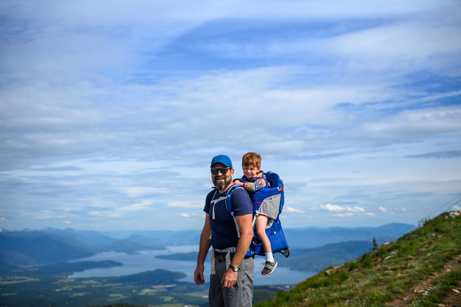 Hiking companions enjoying a sunny day on a mountain trail with scenic mountain vistas in the background.