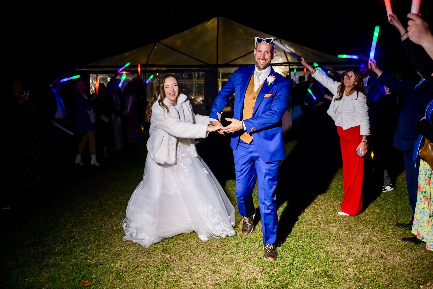 Wedding couple grand exit with guests waving LED light up foam wands creating a festive atmosphere.