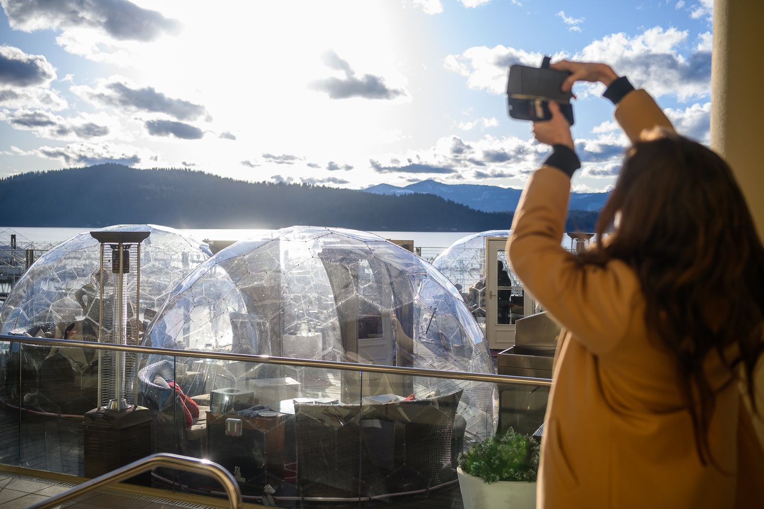 Person taking photo of outdoor dining bubbles with mountain view in background.