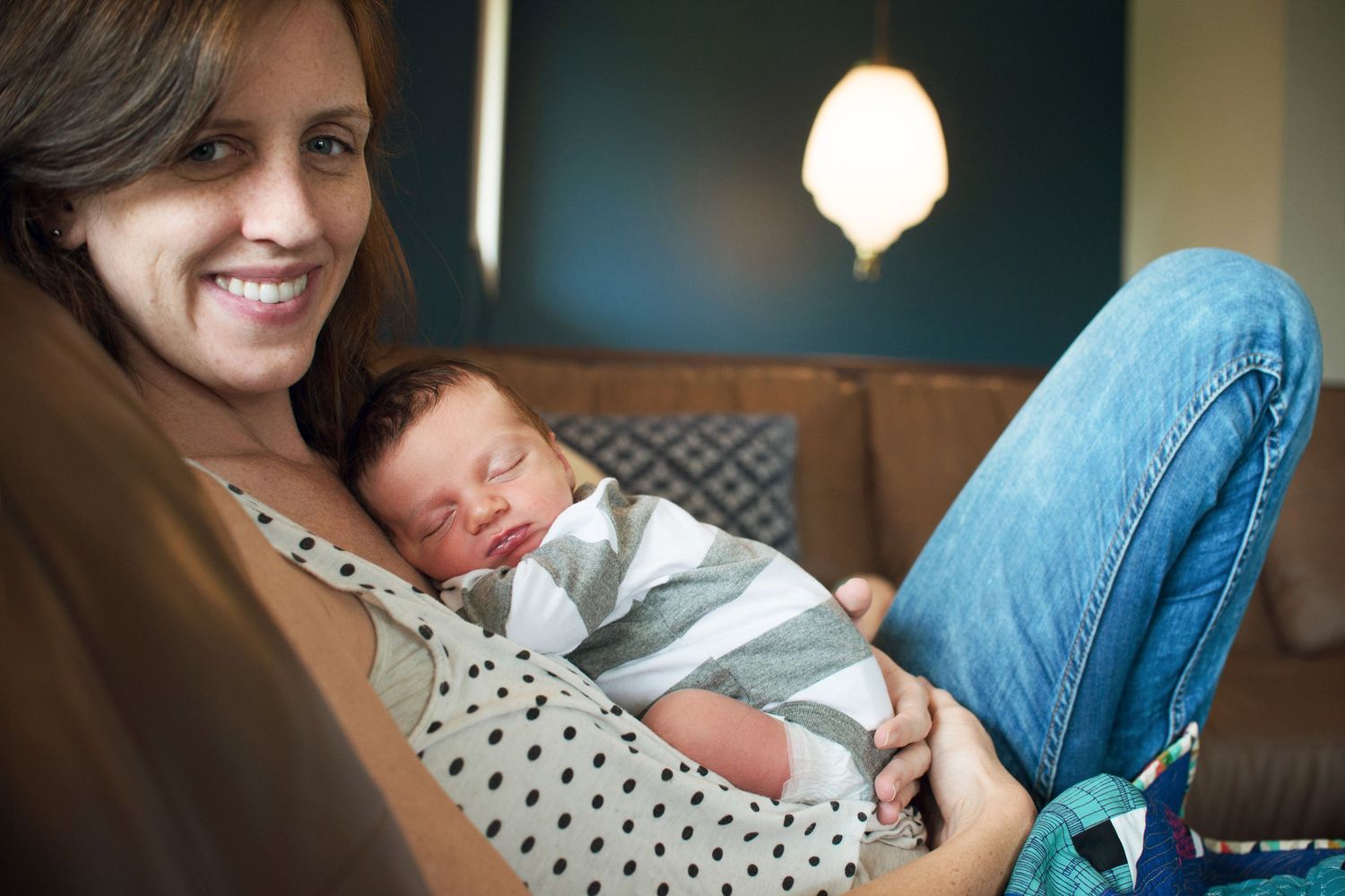 Intimate bonding moment with newborn baby in home setting with soft lighting.