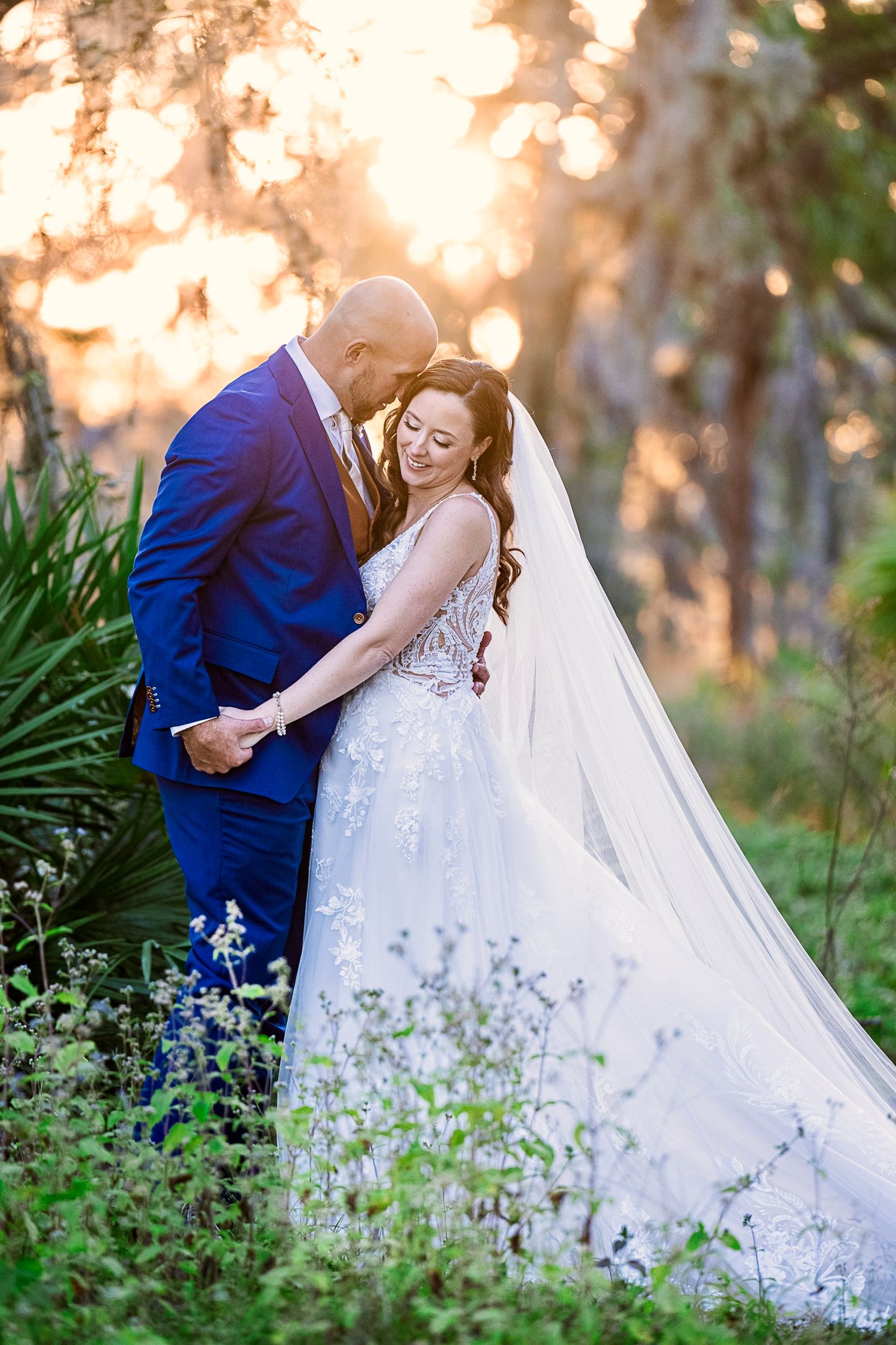 A romantic wedding moment at golden sunset with lush greenery and flowers in the background.