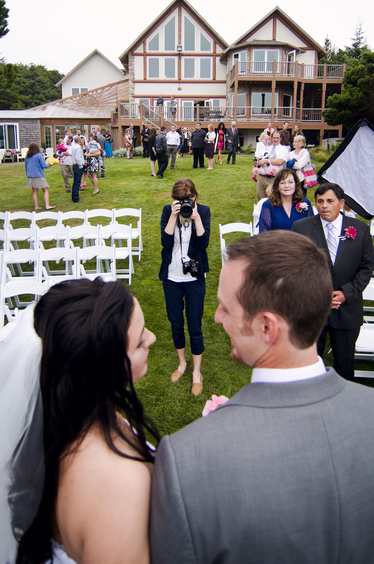 An outdoor wedding setup with white chairs and lodge-style houses in the background.
