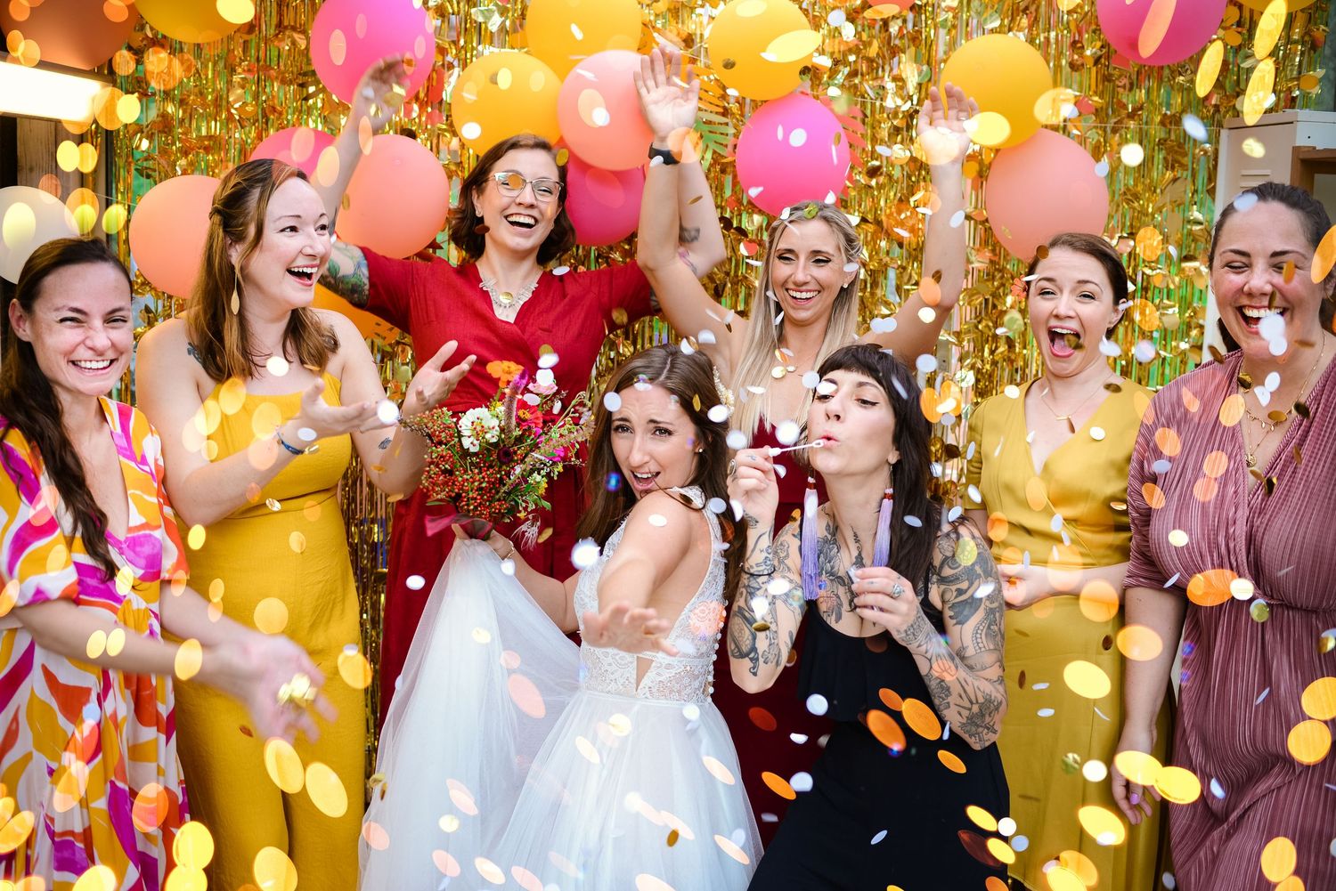 A joyful celebration with people blowing bubbles and holding pink balloons against a golden sunlit background.