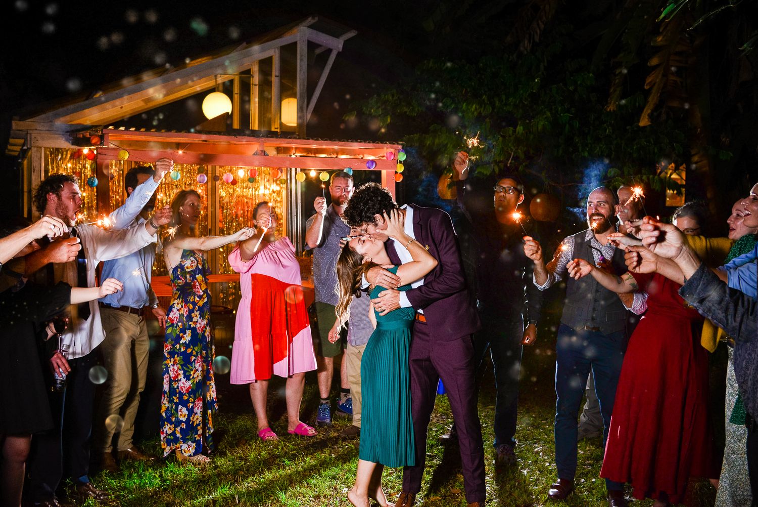 Guests dancing together under string lights at an outdoor evening wedding reception.