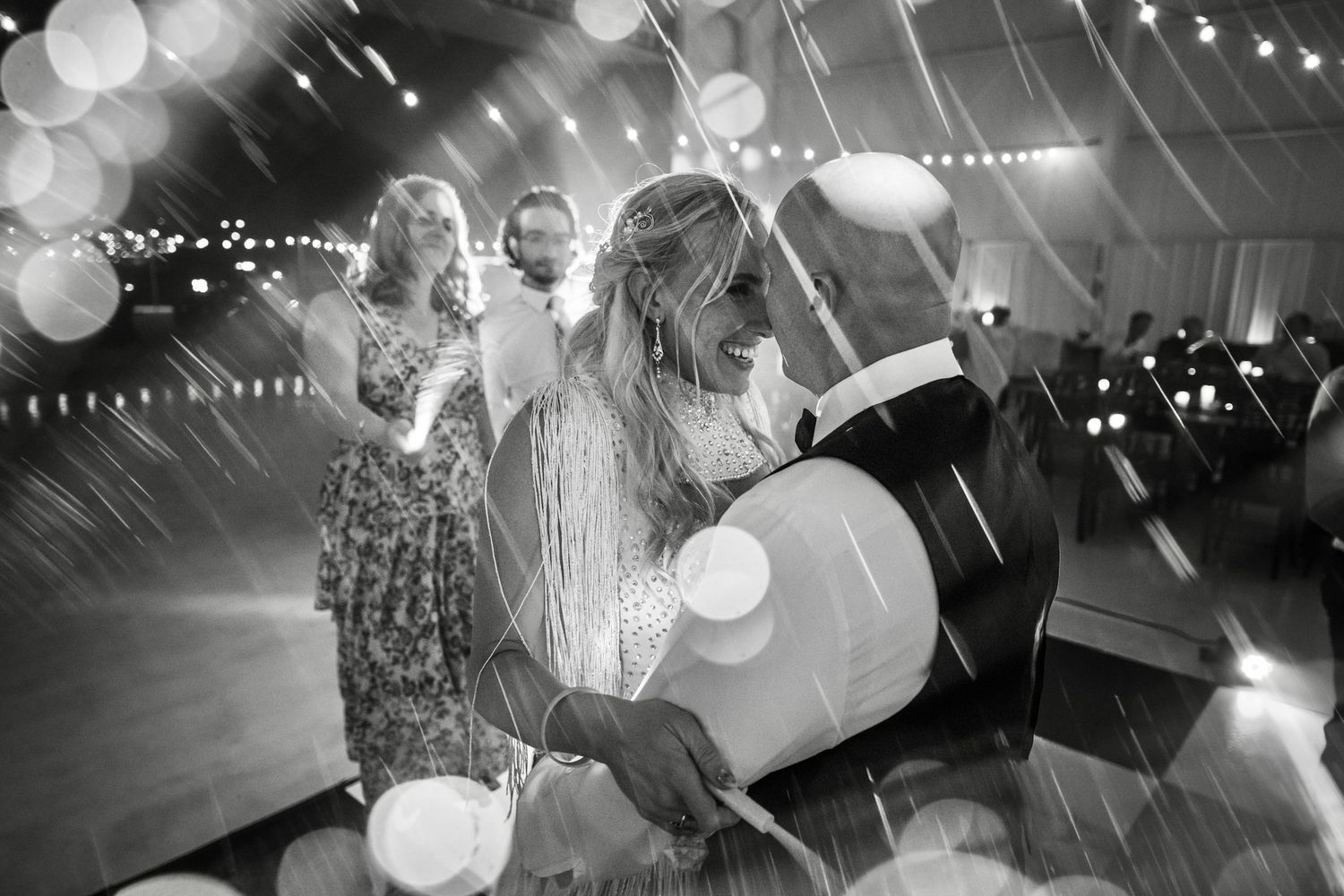 Black and white panoramic sequence of a wedding celebration with string lights and paper lanterns creating a festive atmosphere.