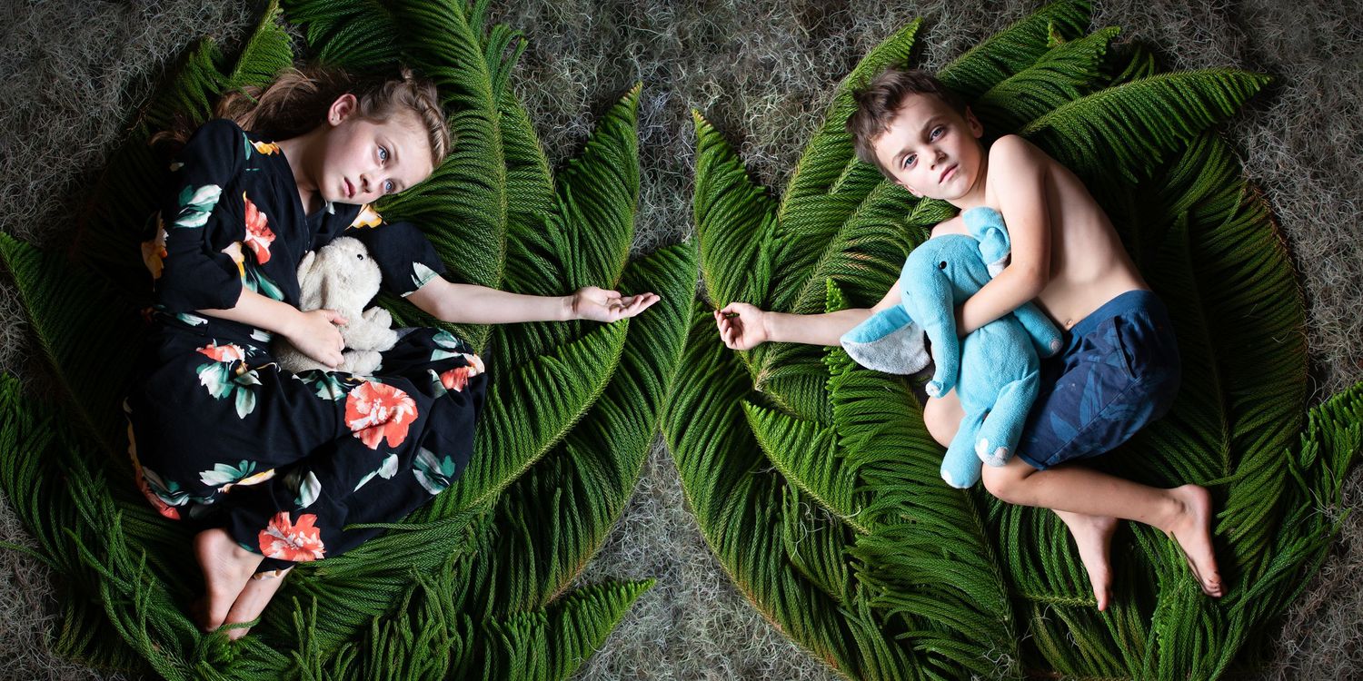 Artistic portrait session featuring tropical palm leaves and dark backdrop.