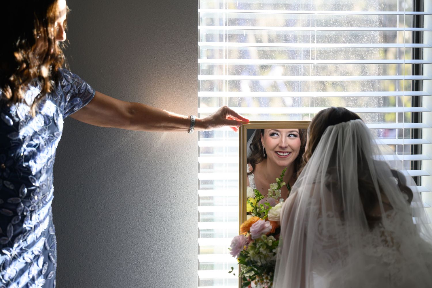 Wedding preparations by a window with a flowing white veil in focus.