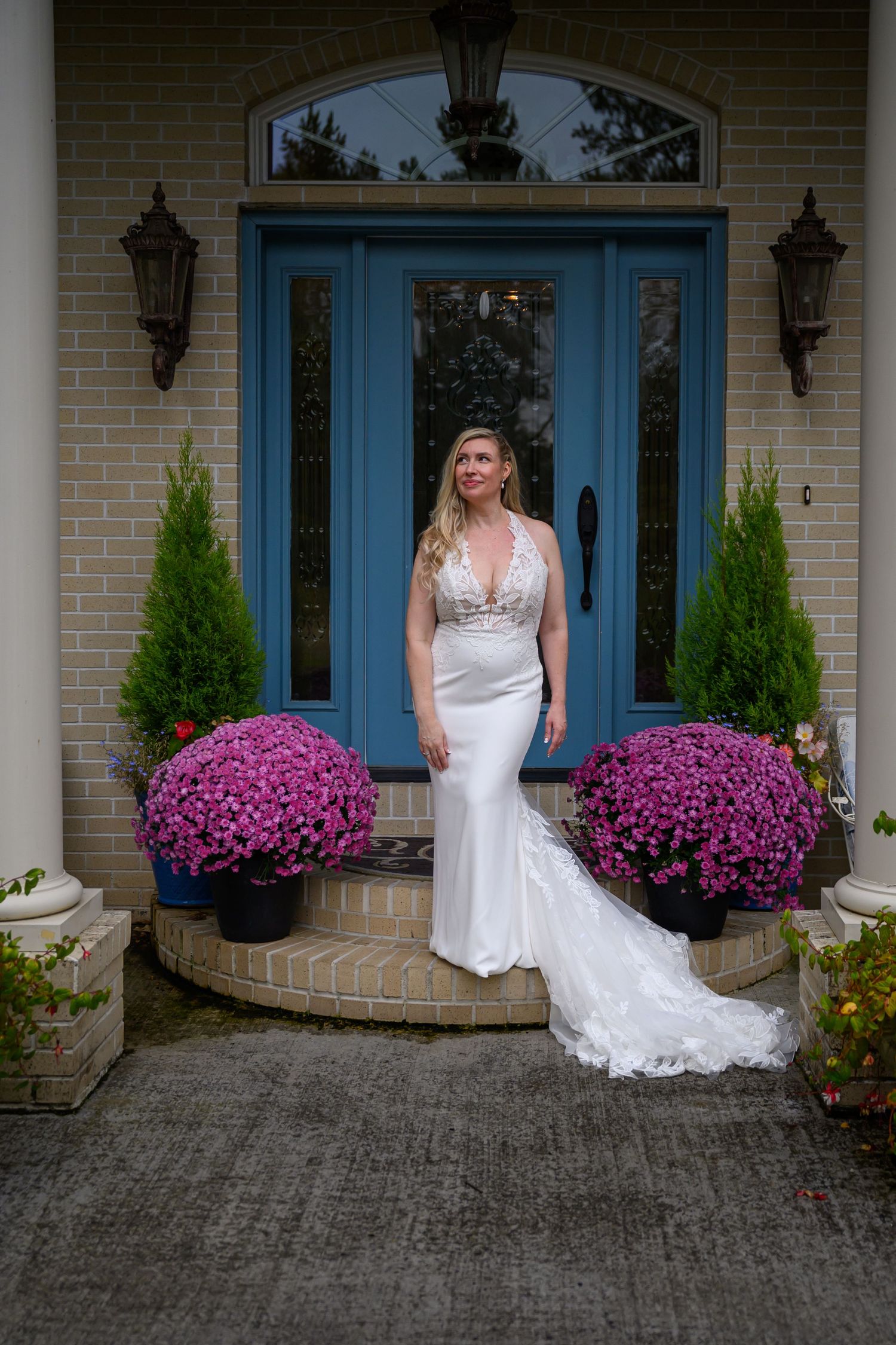 Beautiful wedding portrait on front porch with blue door and vibrant pink mums in decorative planters.