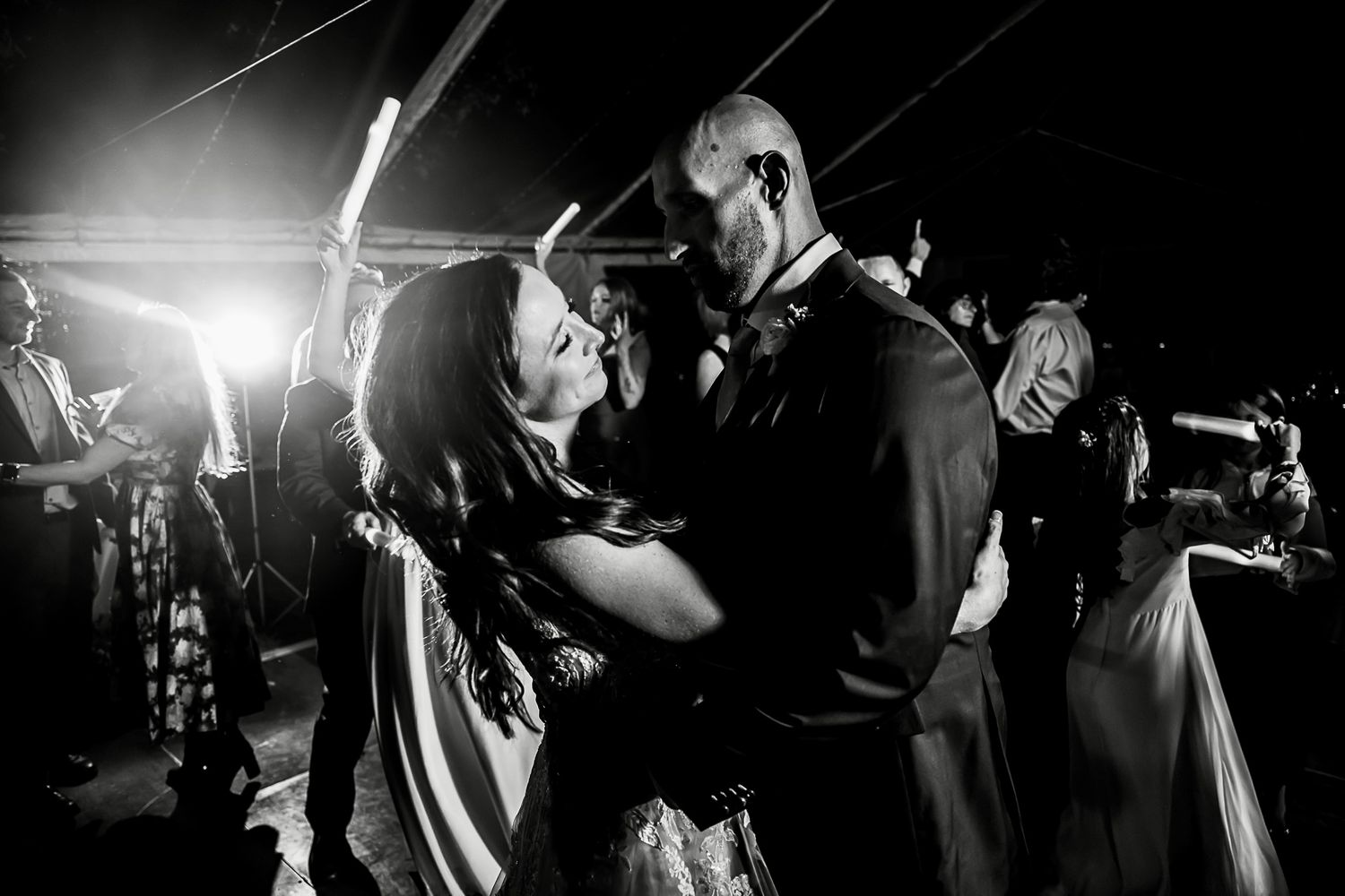 A black and white wedding reception photo shows a couple enjoying their first dance while guests look on in the background.
