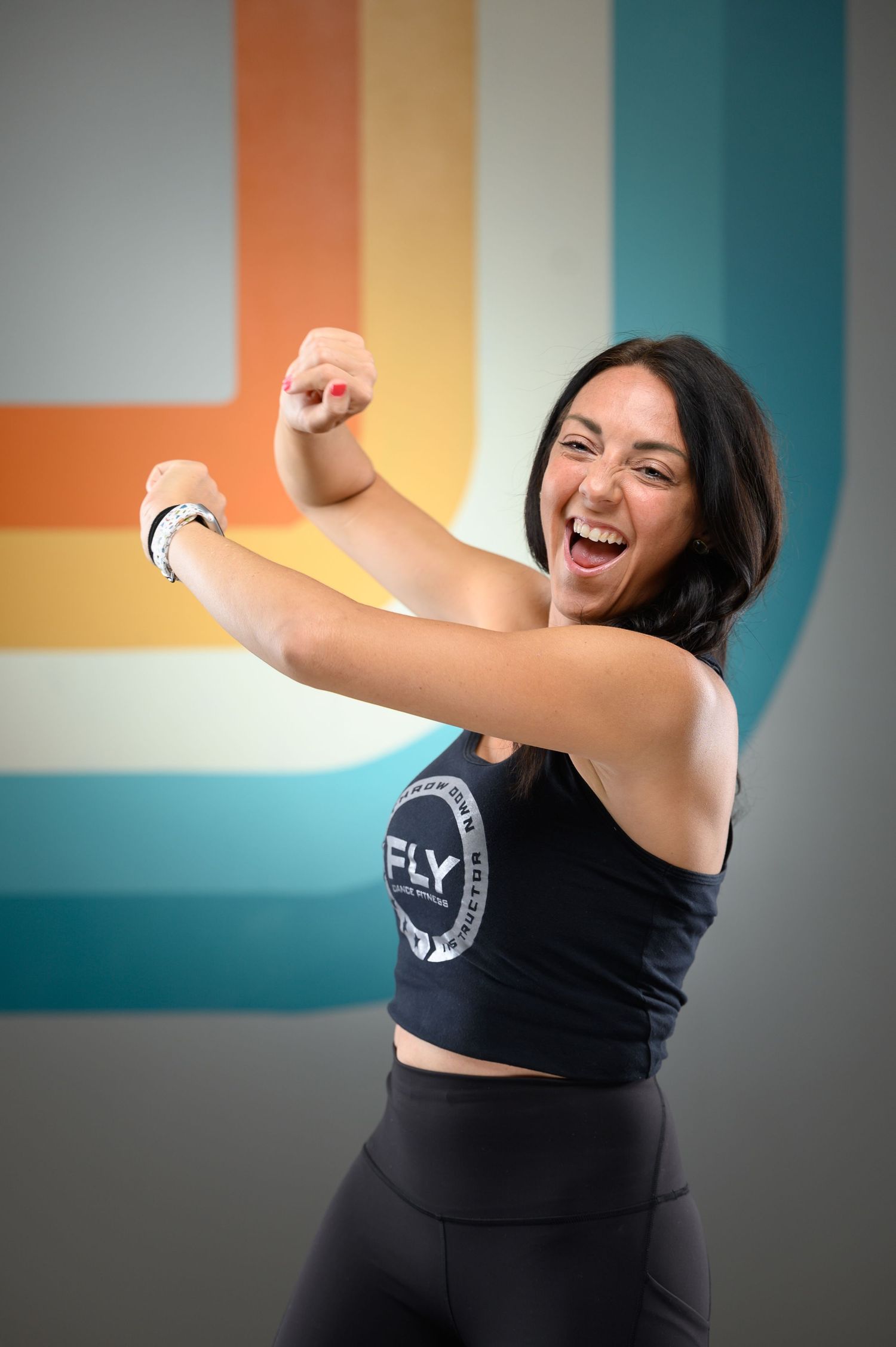 Athletic woman in black workout attire celebrates with energetic dance moves.