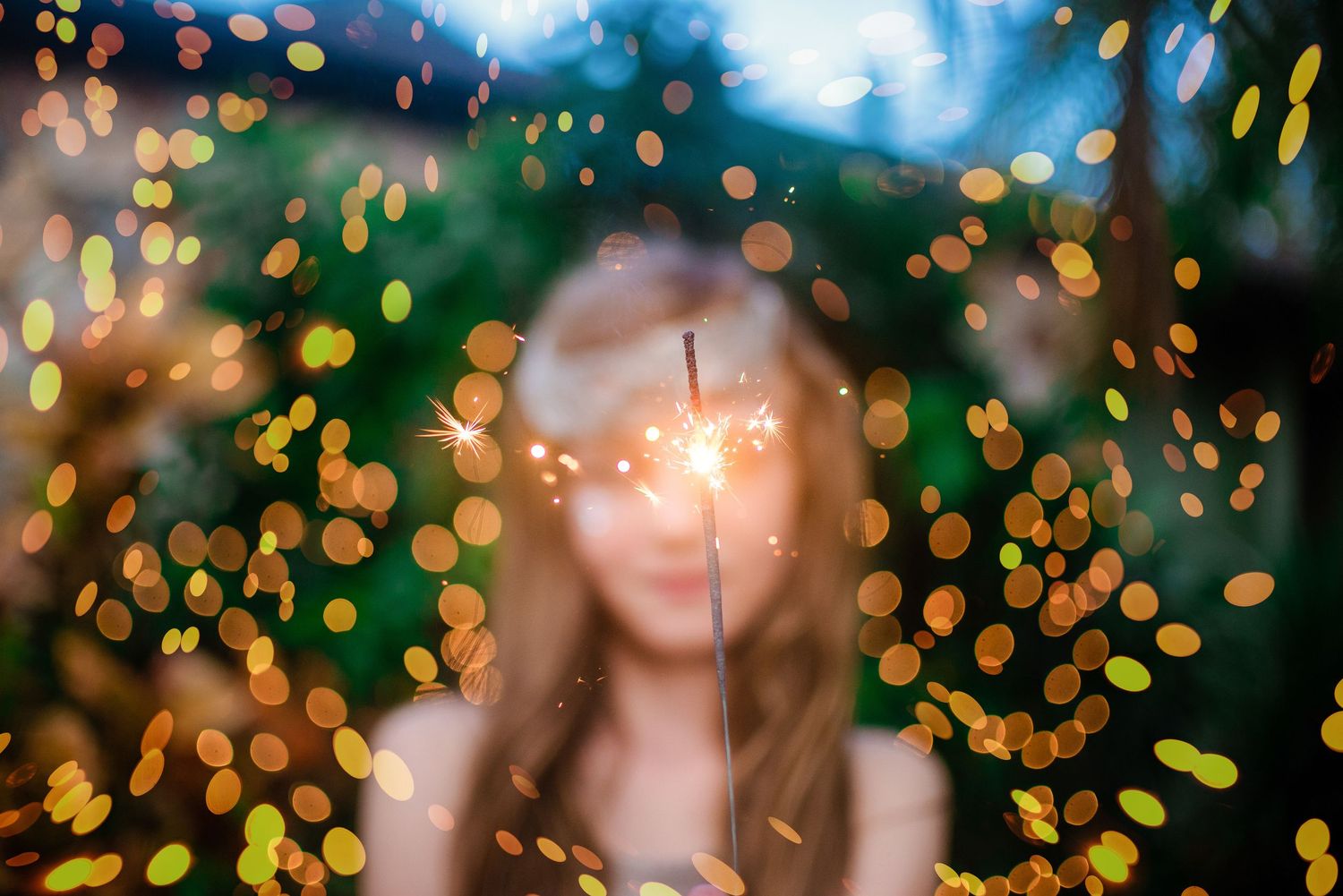 Dreamy portrait with golden bokeh lights creating a magical atmosphere in nature.