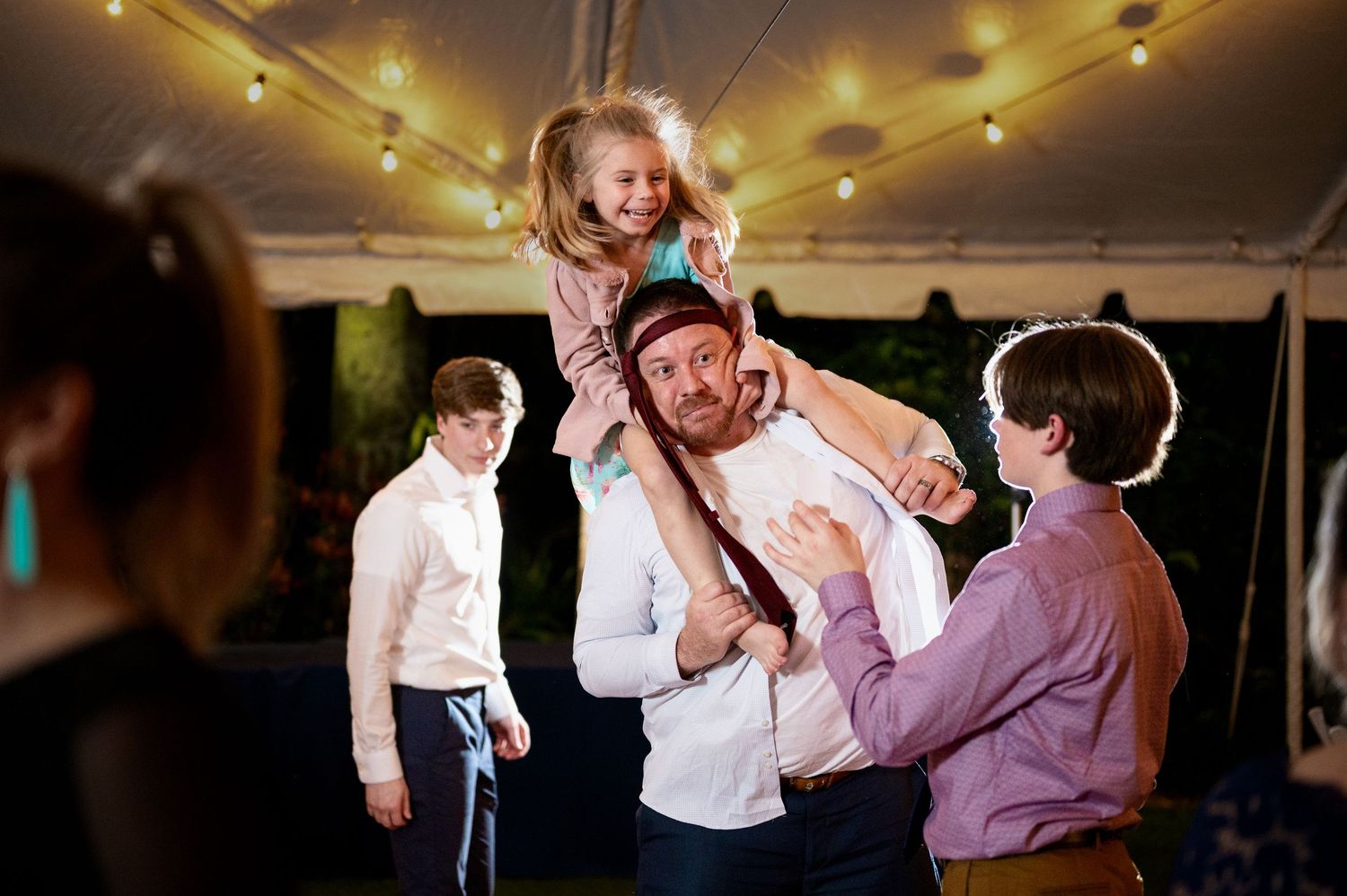 People dancing and celebrating at a lively wedding reception under warm lighting in an indoor venue.