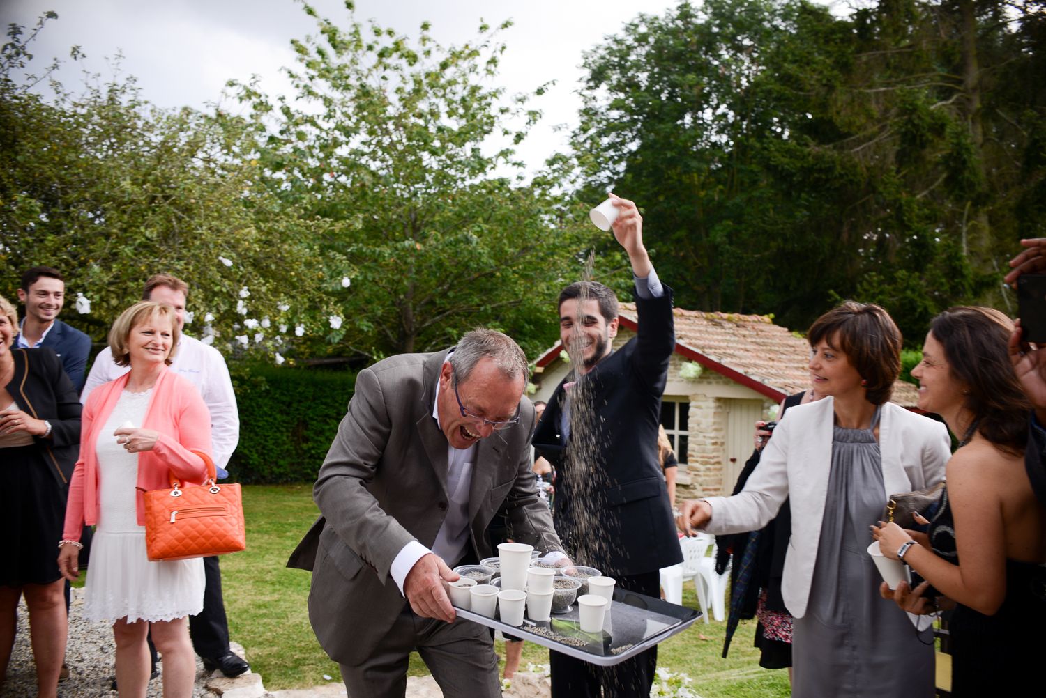 Wedding guests mingling outdoors during daytime garden reception.