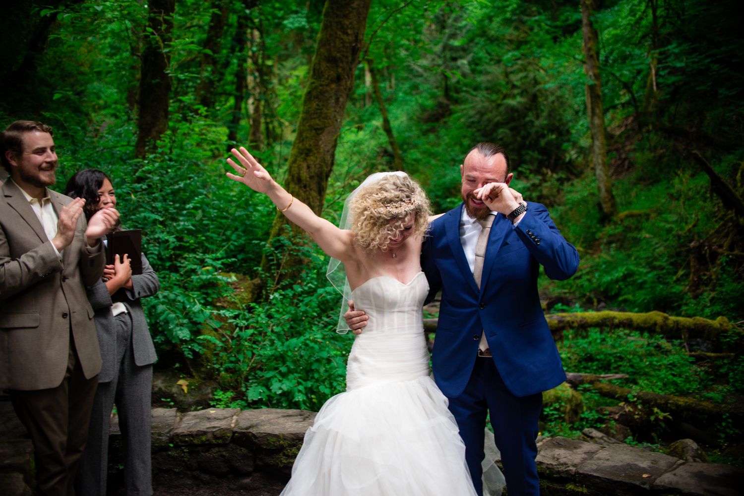 Wedding couple shares a joyful moment in a lush green forest setting.