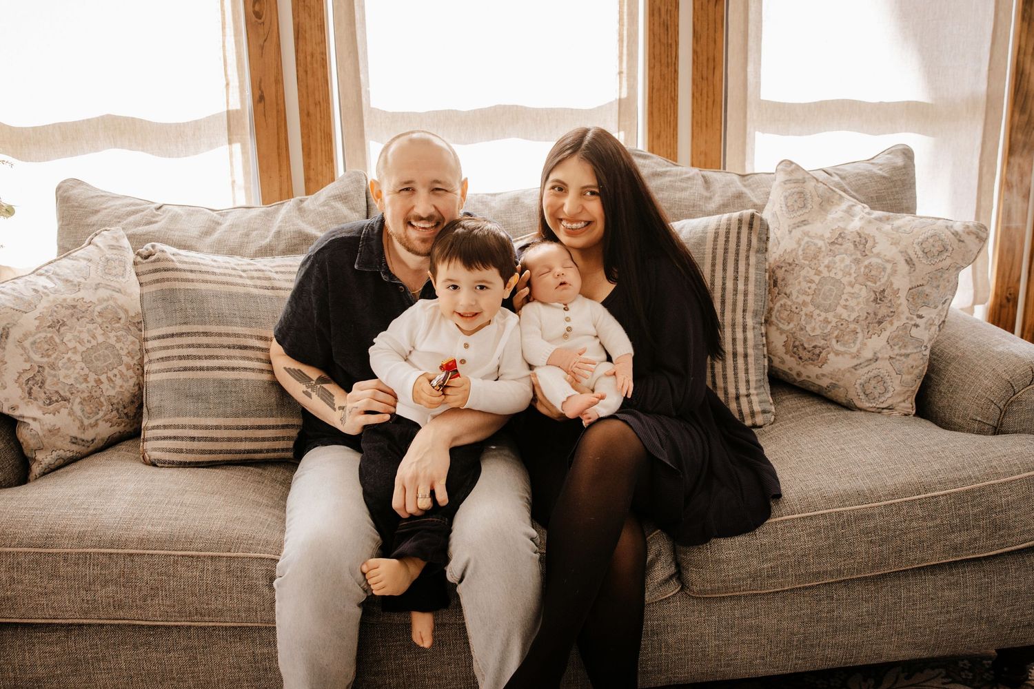 A series of black and white photos showing a family relaxing together on a couch with their baby.