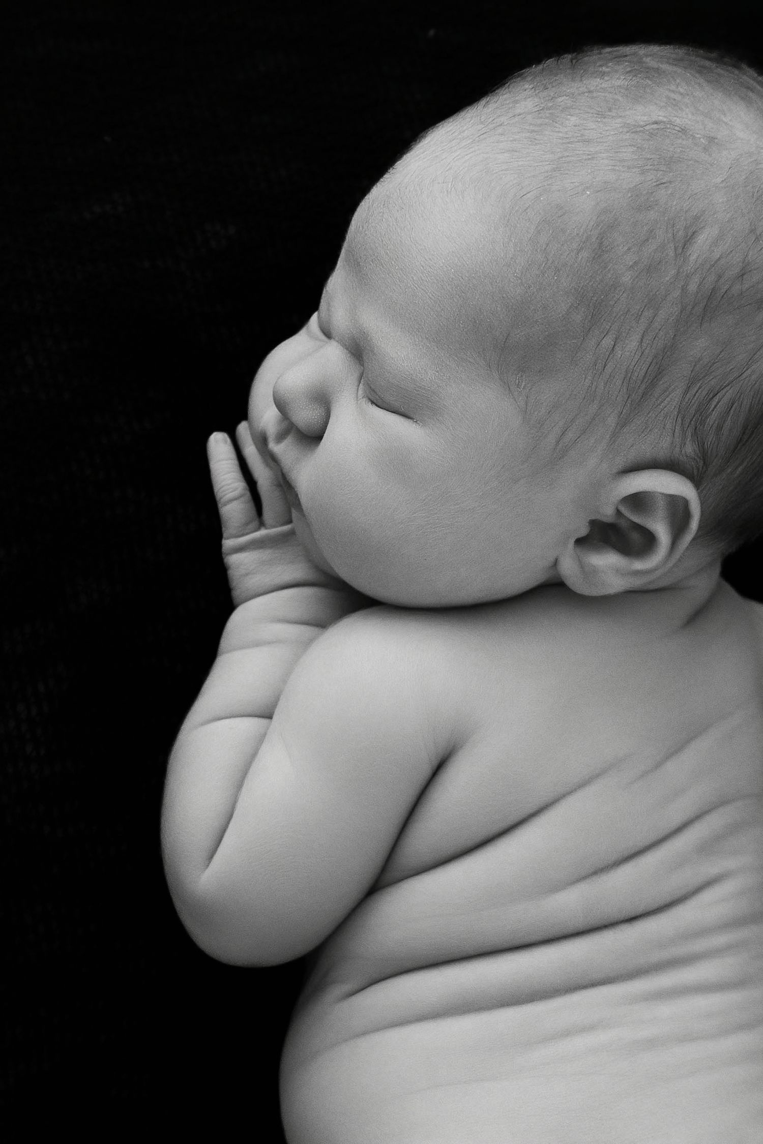 Black and white artistic close-up of sleeping newborn.