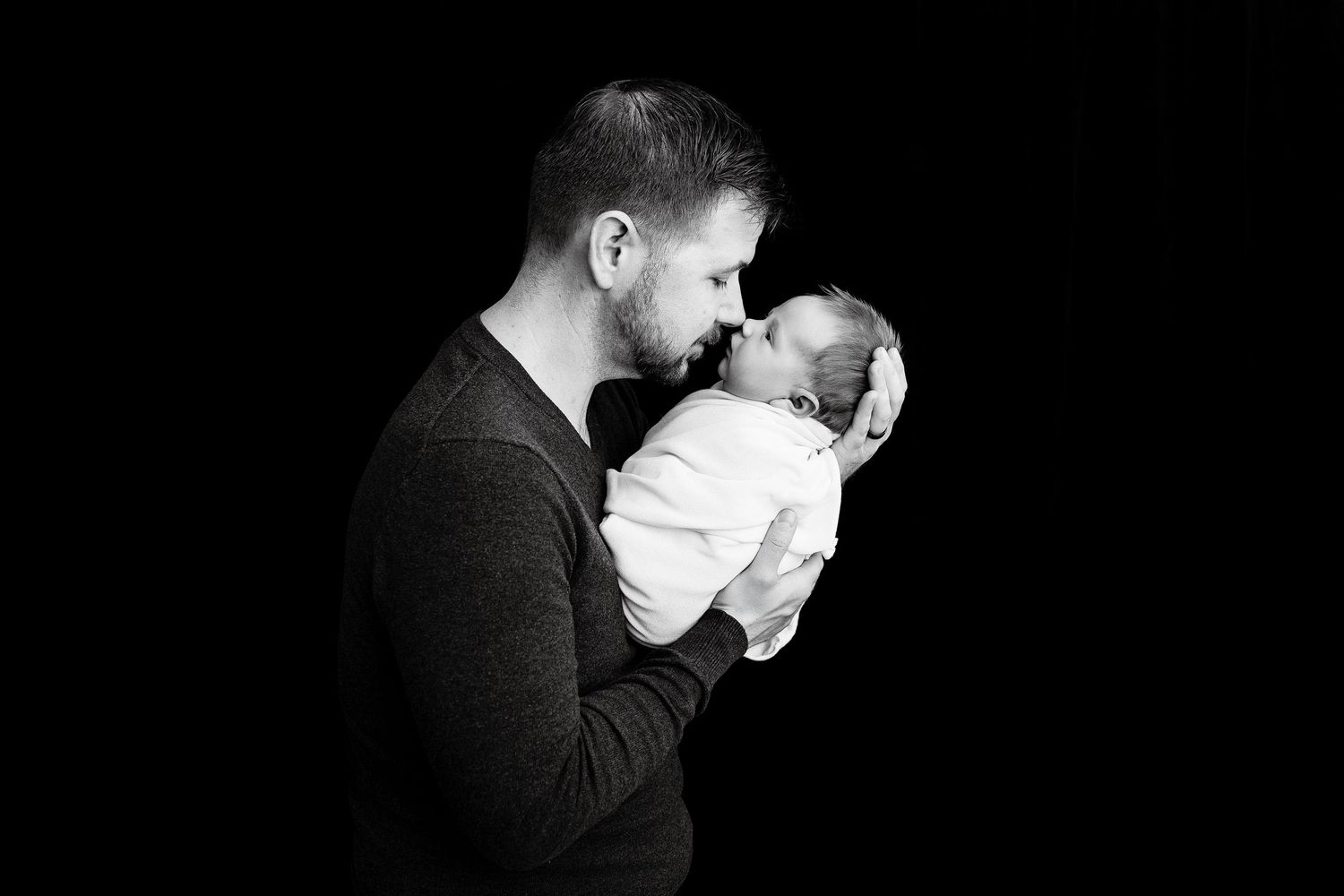 Dramatic black and white photos capturing intimate parent and newborn moments.