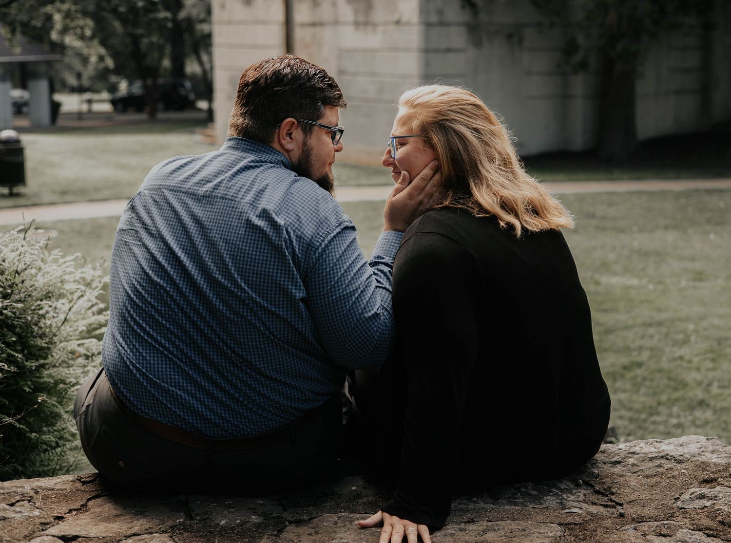 A couple sits close together on stone steps having an intimate conversation outdoors.