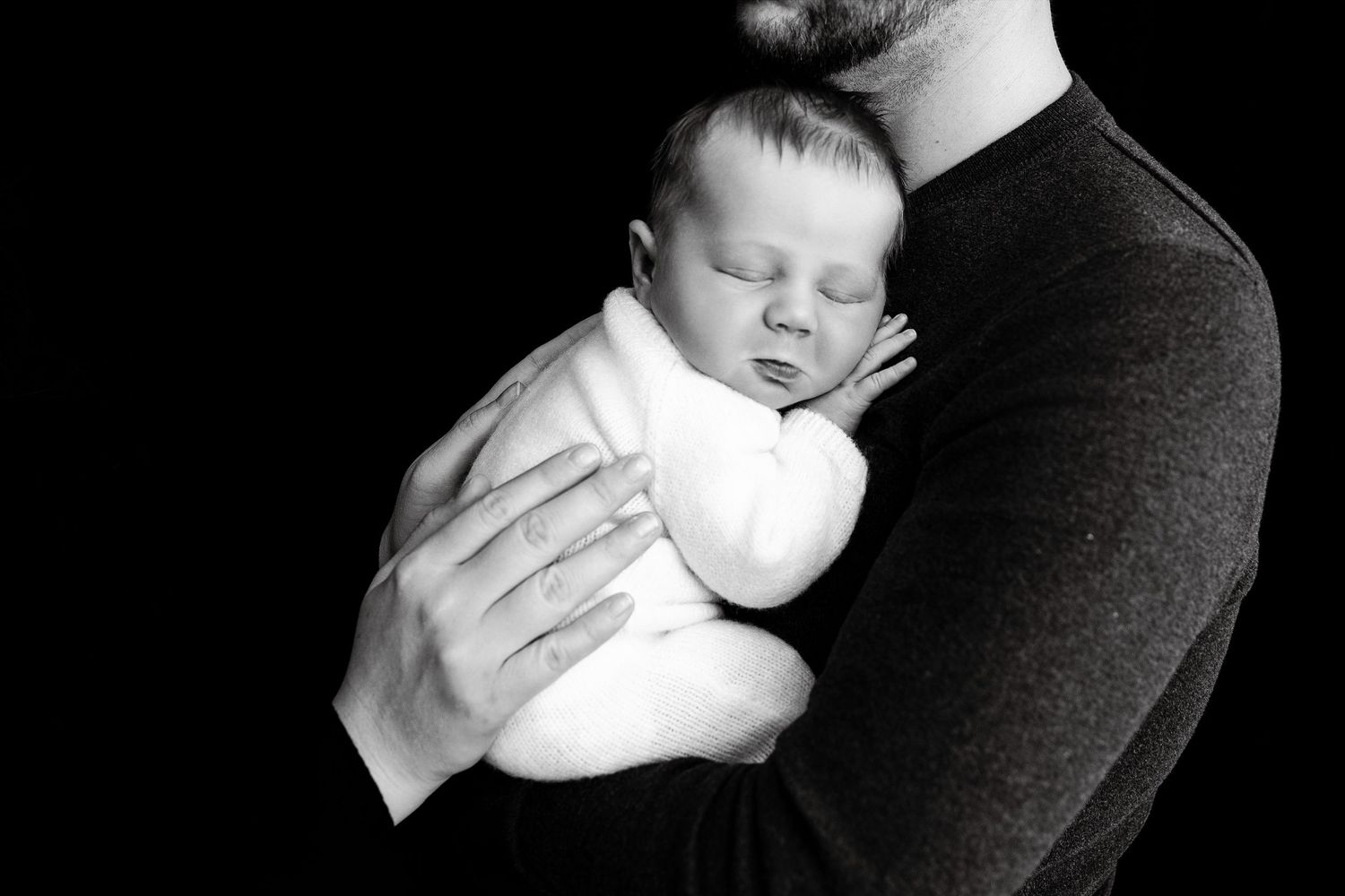 Newborn photography session featuring black and white portraits with gentle poses and wraps.