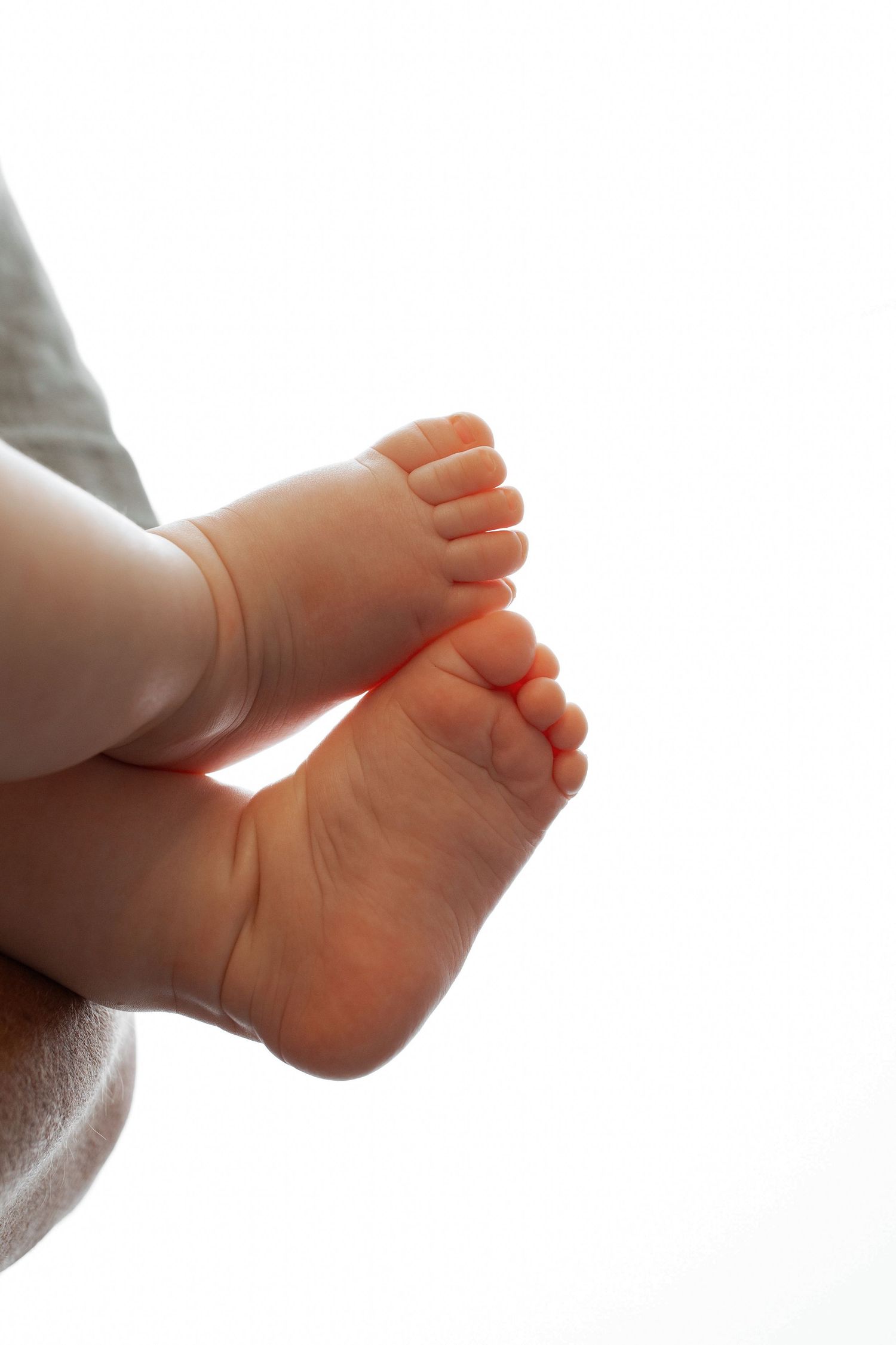 Close-up of tiny newborn baby feet and toes against a white background.