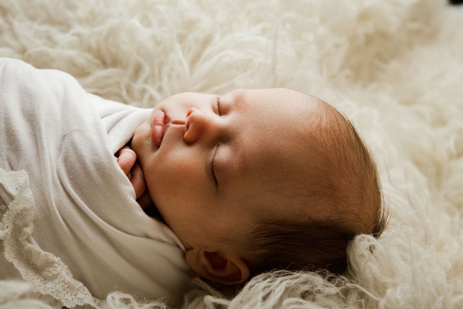 A sleeping baby lies peacefully on white bedding in a series of connected photos showing different angles.