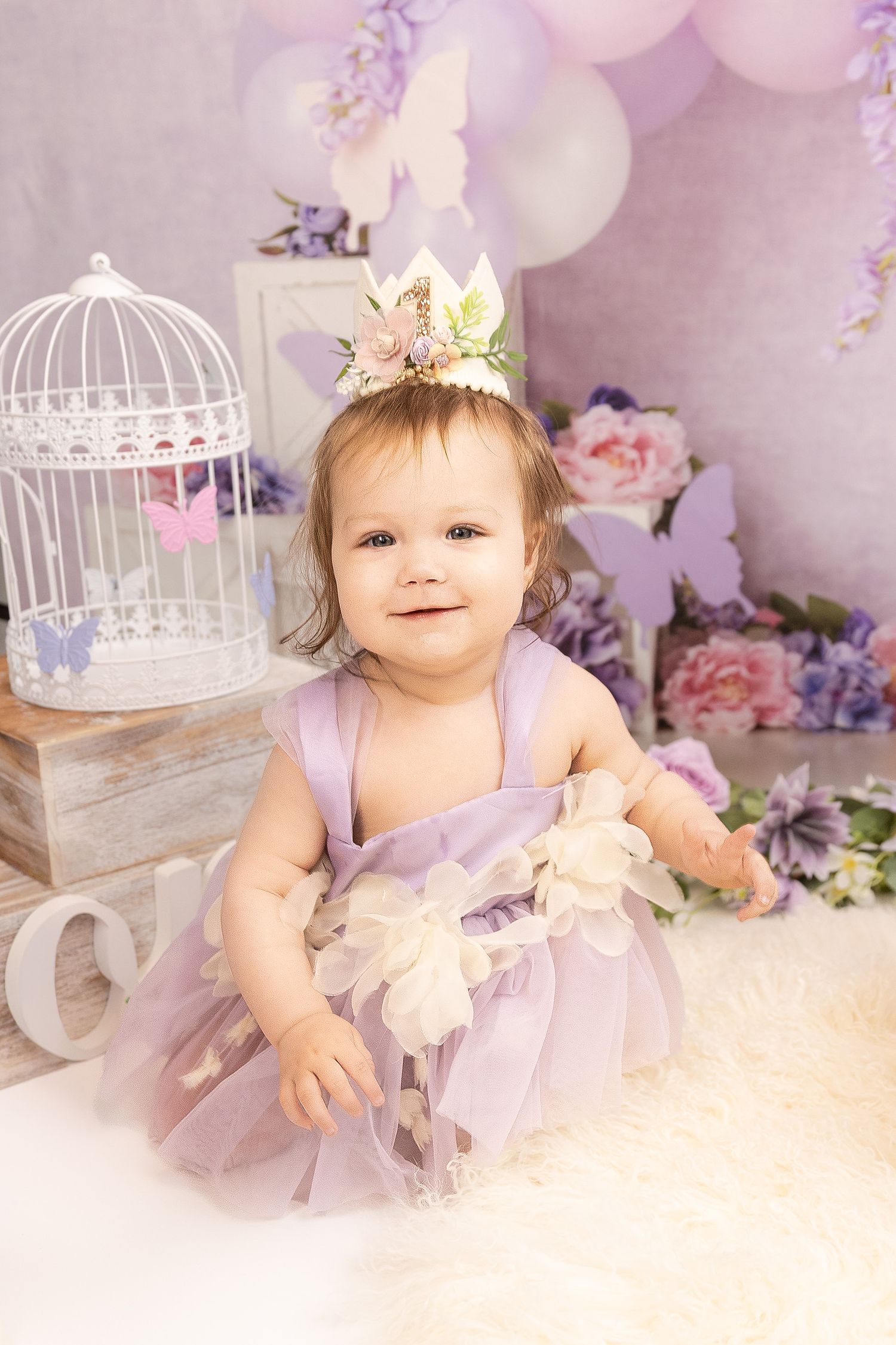 Decorative white birdcages and pastel balloons create a dreamy backdrop with soft pink and purple floral accents.