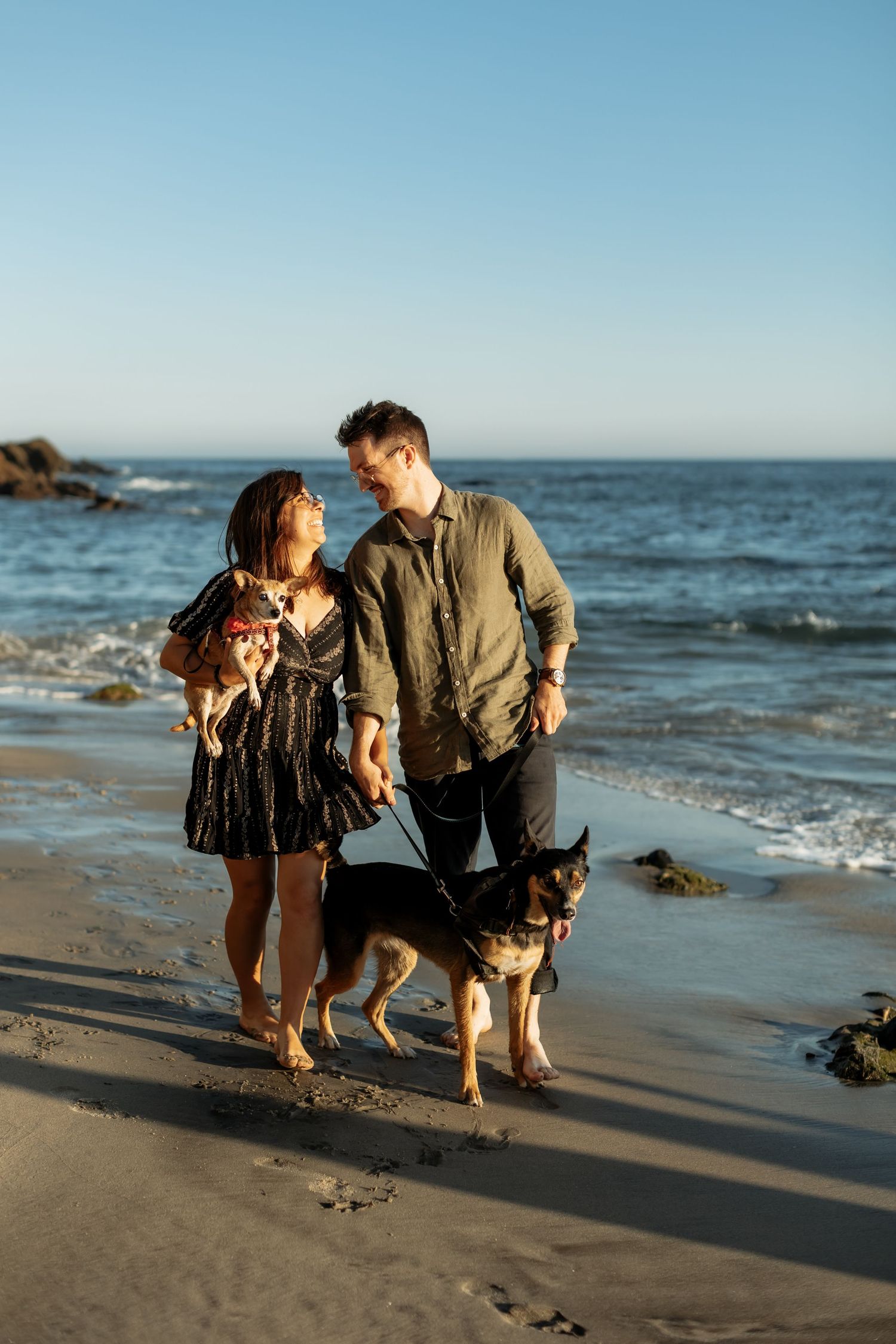 A couple walking along the beach with their dogs in Laguna Beach, ca for a couples photo session